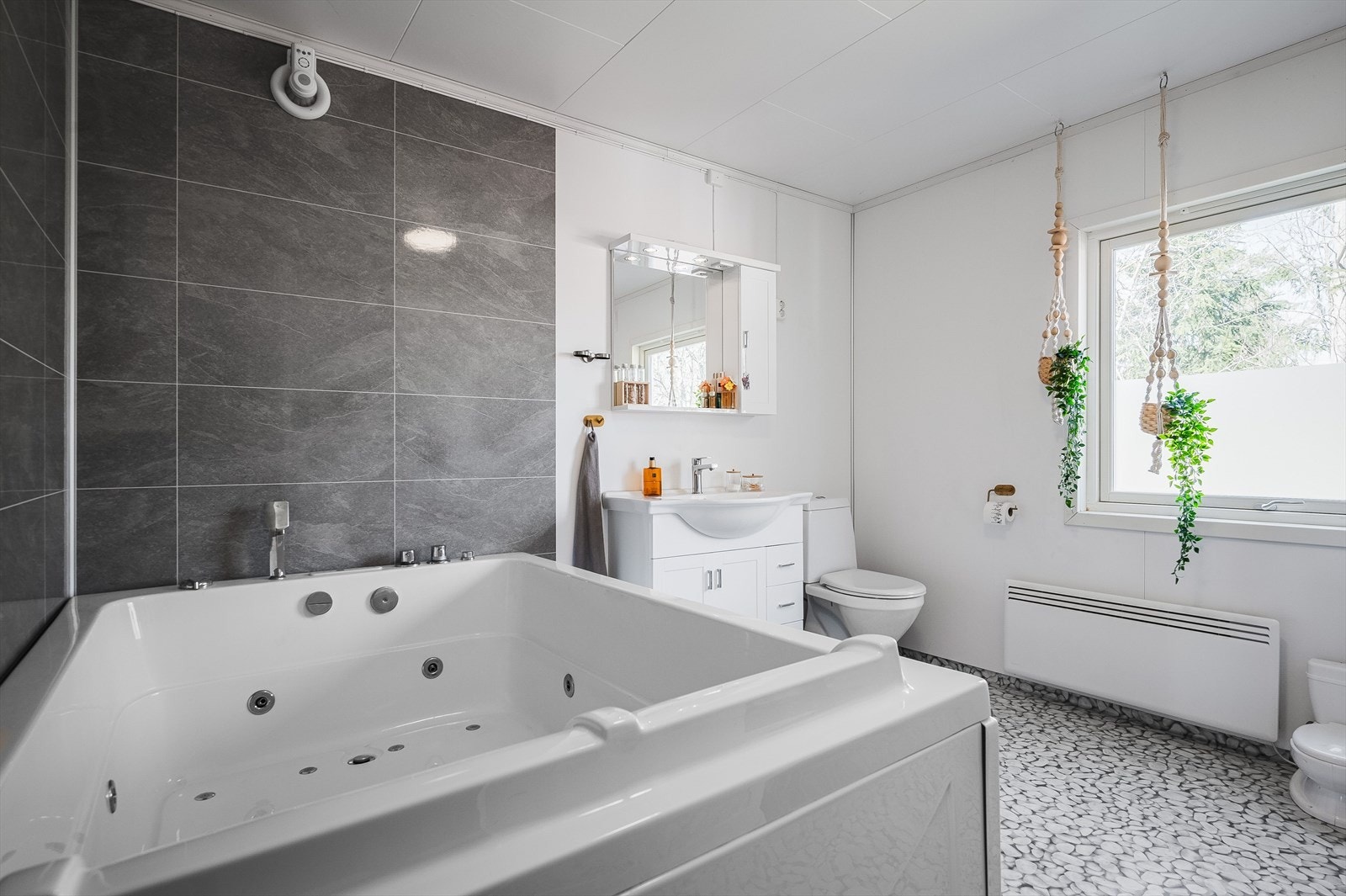 Det største baderommet har belegg på gulv, våtromsplater på veggene, elektrisk styrt vifte og et stort vindu som slipper inn dagslys. Galleribilde