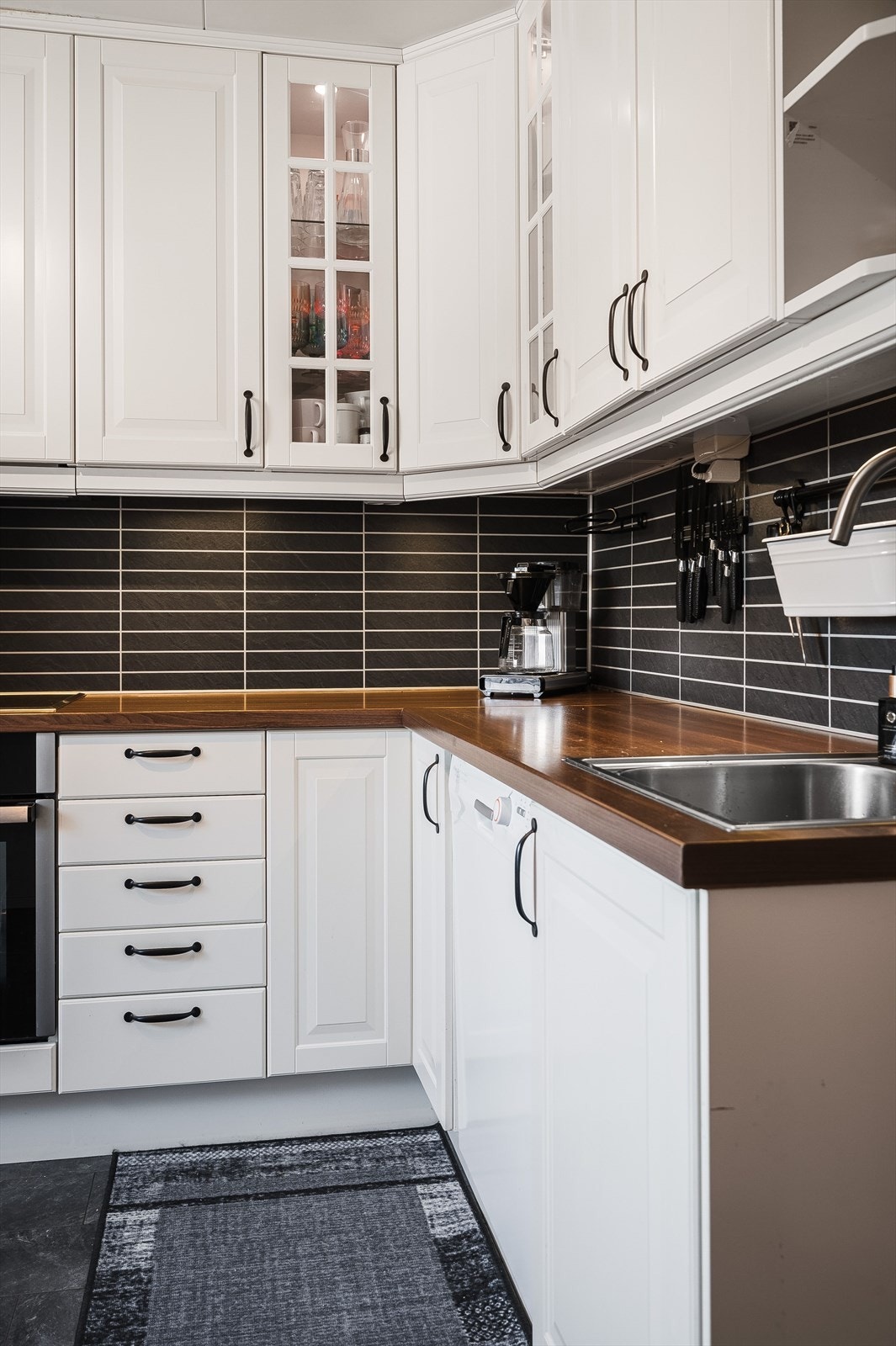 Praktisk med flisimitasjonsplater i benkeryggen og takhøye overskap med belysning under. Galleribilde