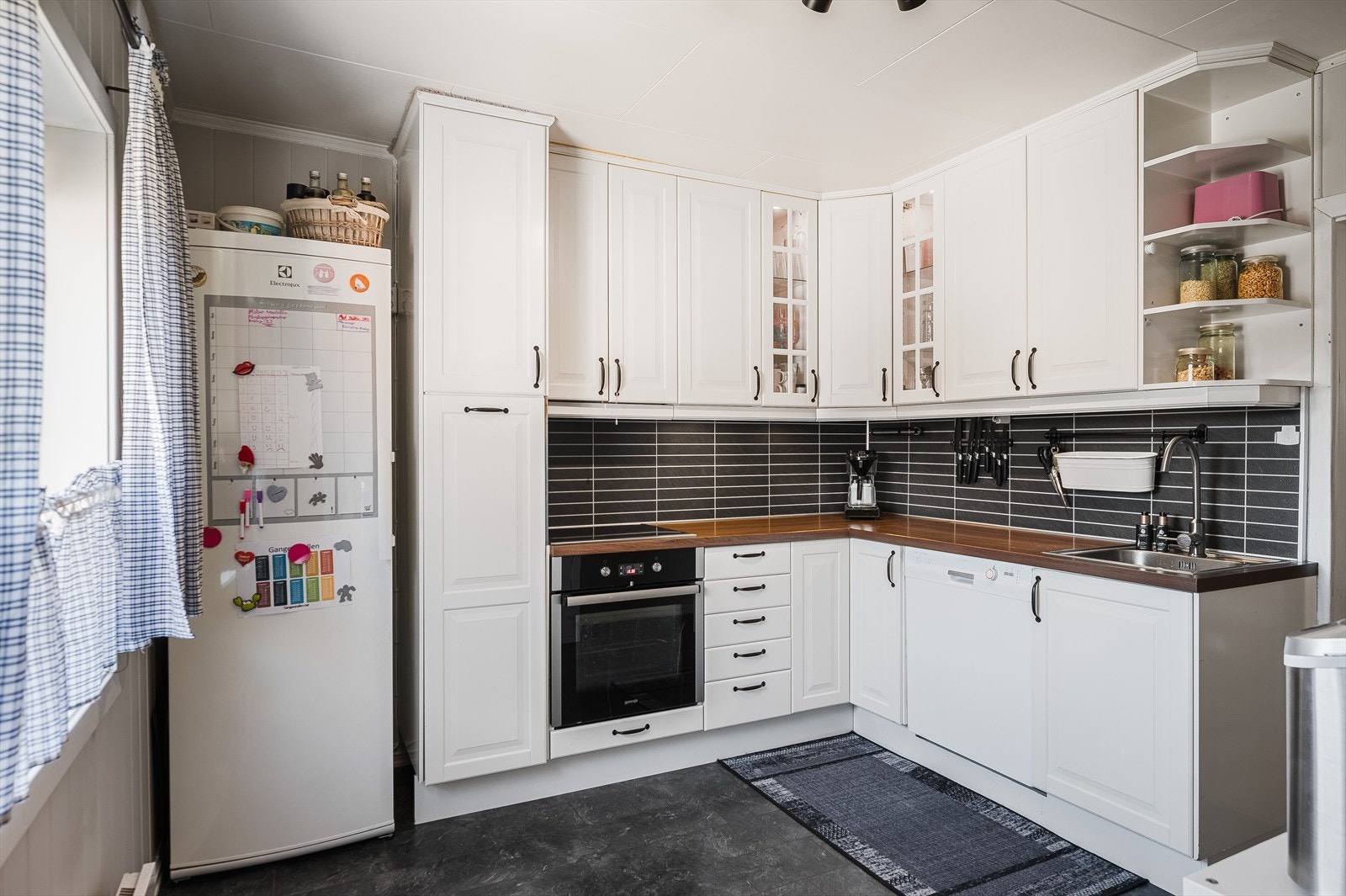 Tidløs kjøkkeninnredning med lyse profilerte fronter og laminert benkeplate med nedfelt oppvaskkum. Galleribilde