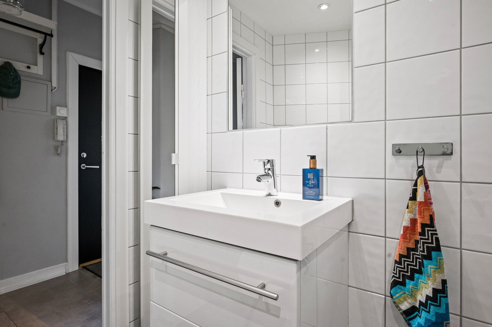 Innredningen er med vegghengt servantinnredning og speil med belysning over servant. Badet har også eget dusjhjørne med innfellbare, buede glassdører og dusjarmatur tilkoblet hånddusj. Galleribilde