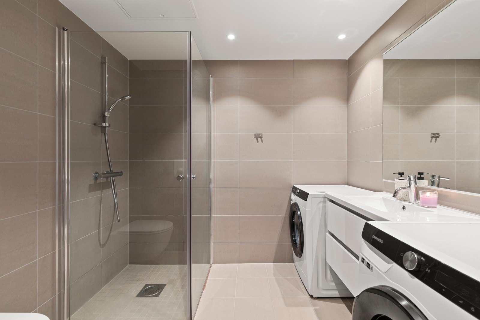 Badet består av heldekkende porselen servant med underskap og speil, vegghengt toalett, og dusjhjørne med innfellbare glassdører. Galleribilde