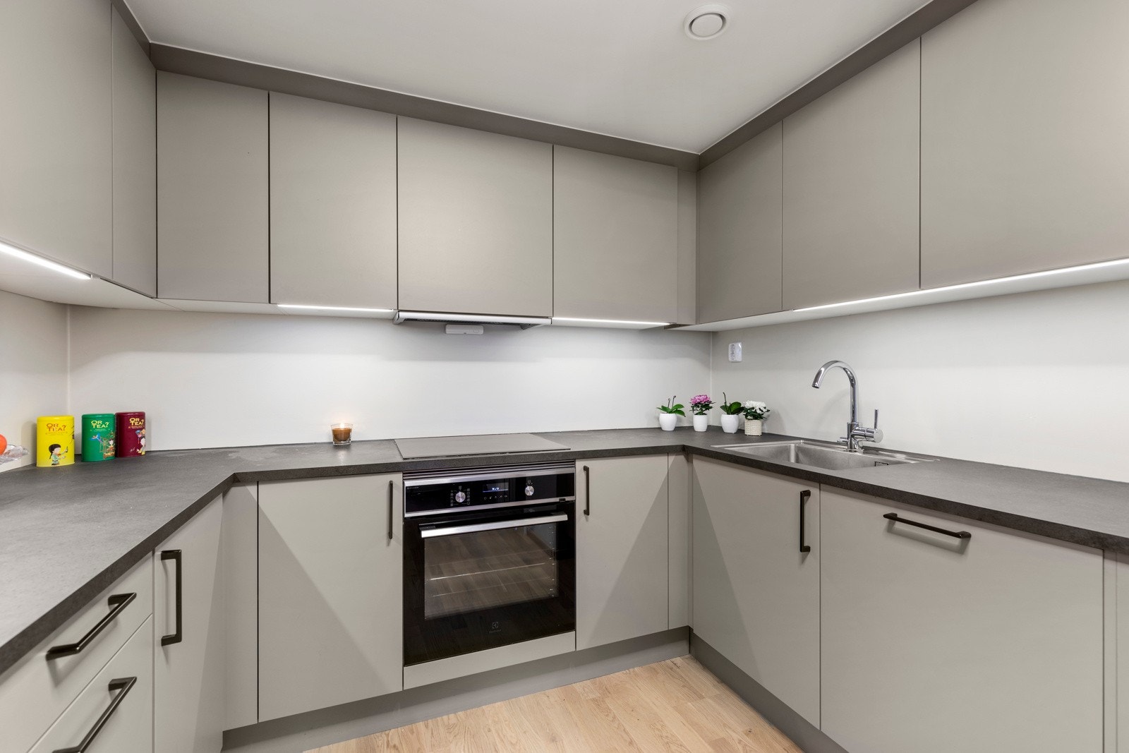 HTH kjøkkeninnredning med grå/beige glatte fronter og laminerte benkeplater i imitert stein. Galleribilde