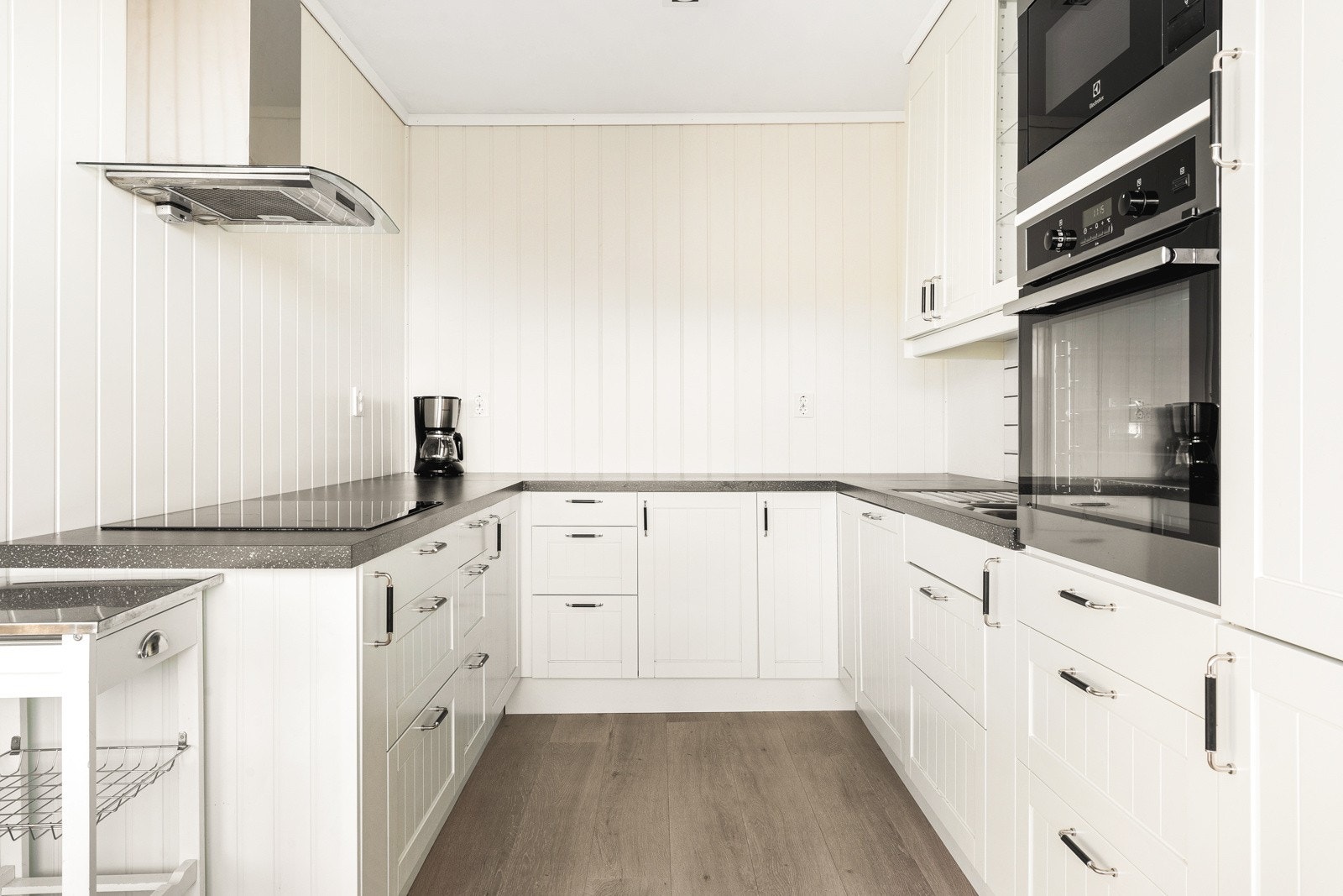 Innredningen består av hvite profilerte fronter, kjøkkenvask i stål nedfelt i benkeplate av laminat, samt integrert kjøl/fryseskap. Galleribilde