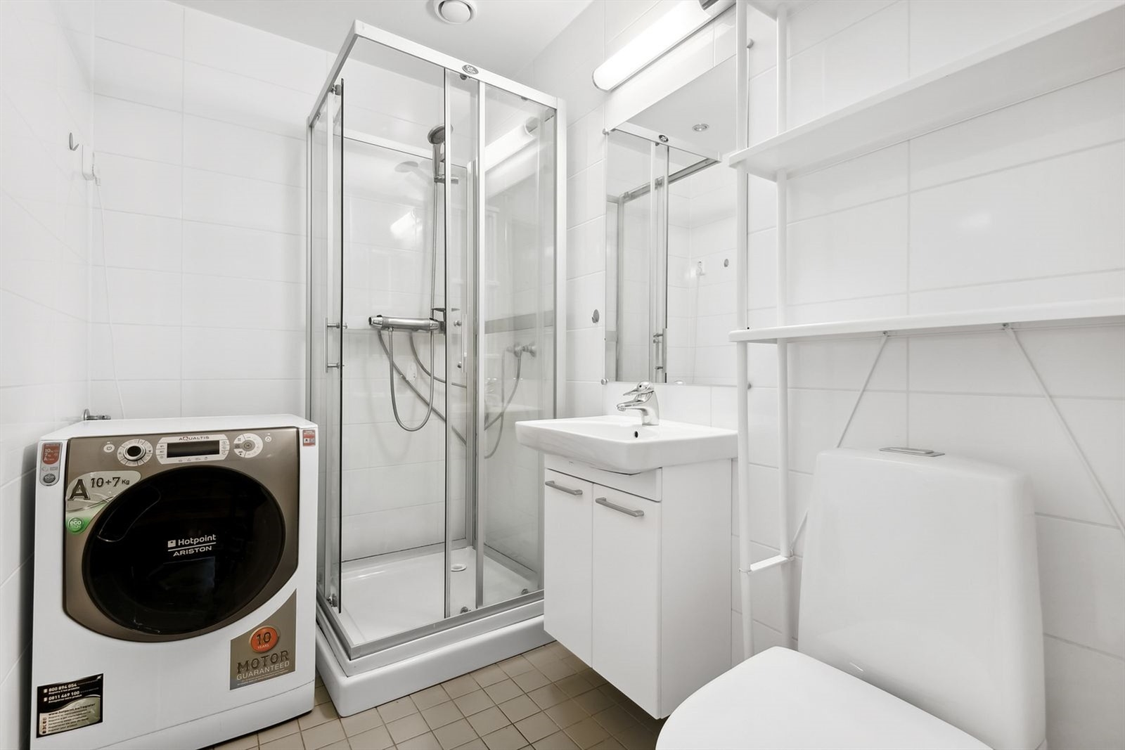 Flislagt bad utstyrt med gulvvarme, servant med underskap og speil, dusjhjørne og wc. Vaskemaskin medfølger. Galleribilde