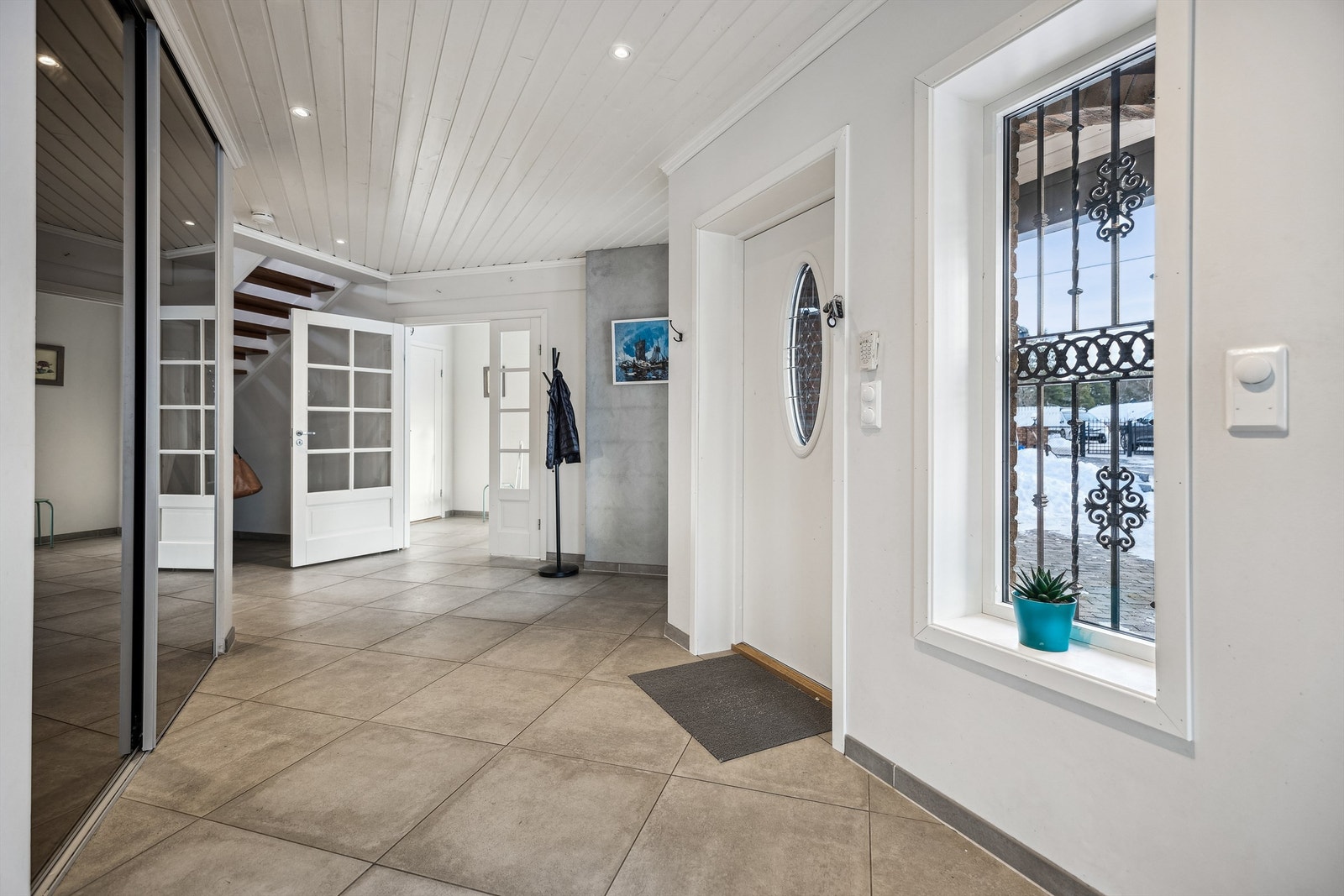 Romslig entré med flislagt gulv og stor skyvedørsgarderobe med speildører. Galleribilde