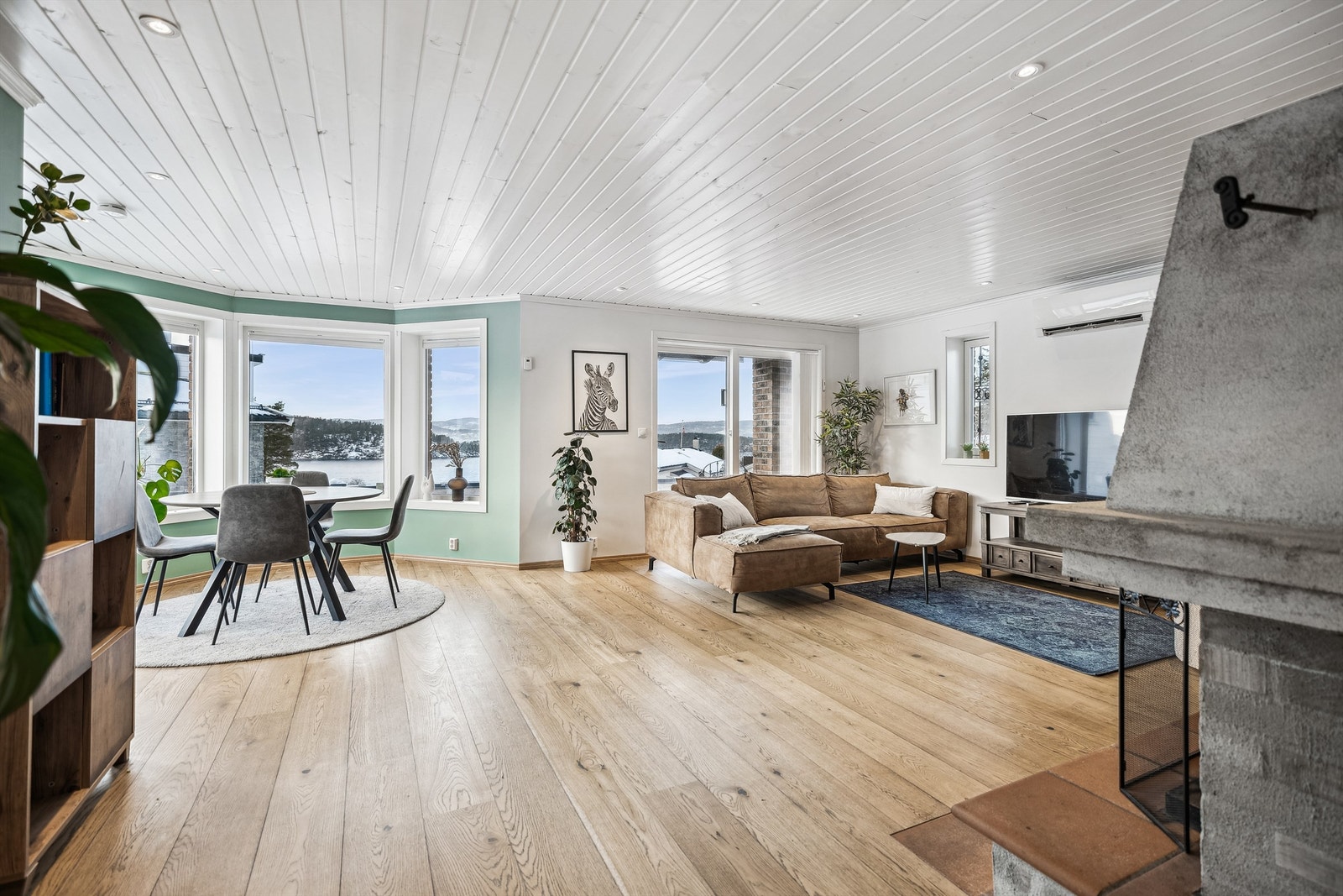 Stuen er av god størrelse og store vinduer mot utsikten fyller rommet med naturlig lys og skaper en god atmosfære Galleribilde