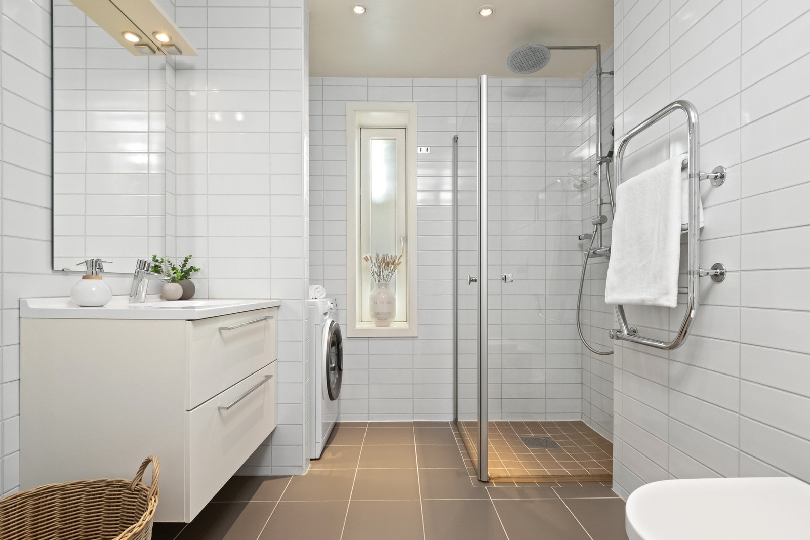 Leiligheten har et pent bad med hvite fliser på veggene, downlights i himlingen og mørke fliser på gulv med elektrisk gulvvarme. Galleribilde