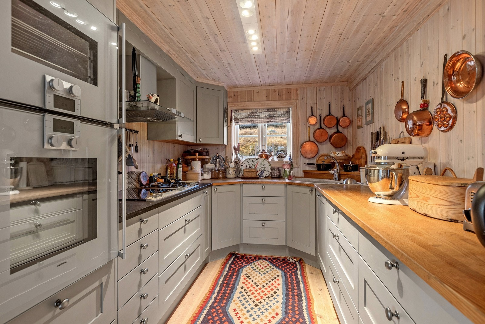 Hyttas kjøkken er designet for å maksimere oppbevaringsplassen, uten at det går på bekostning av bevegelsesfriheten. Kjøkkenet er innredet med profilerte fronter og benkeplate i heltre og stein, som gir en robust og holdbar arbeidsflate. Galleribilde