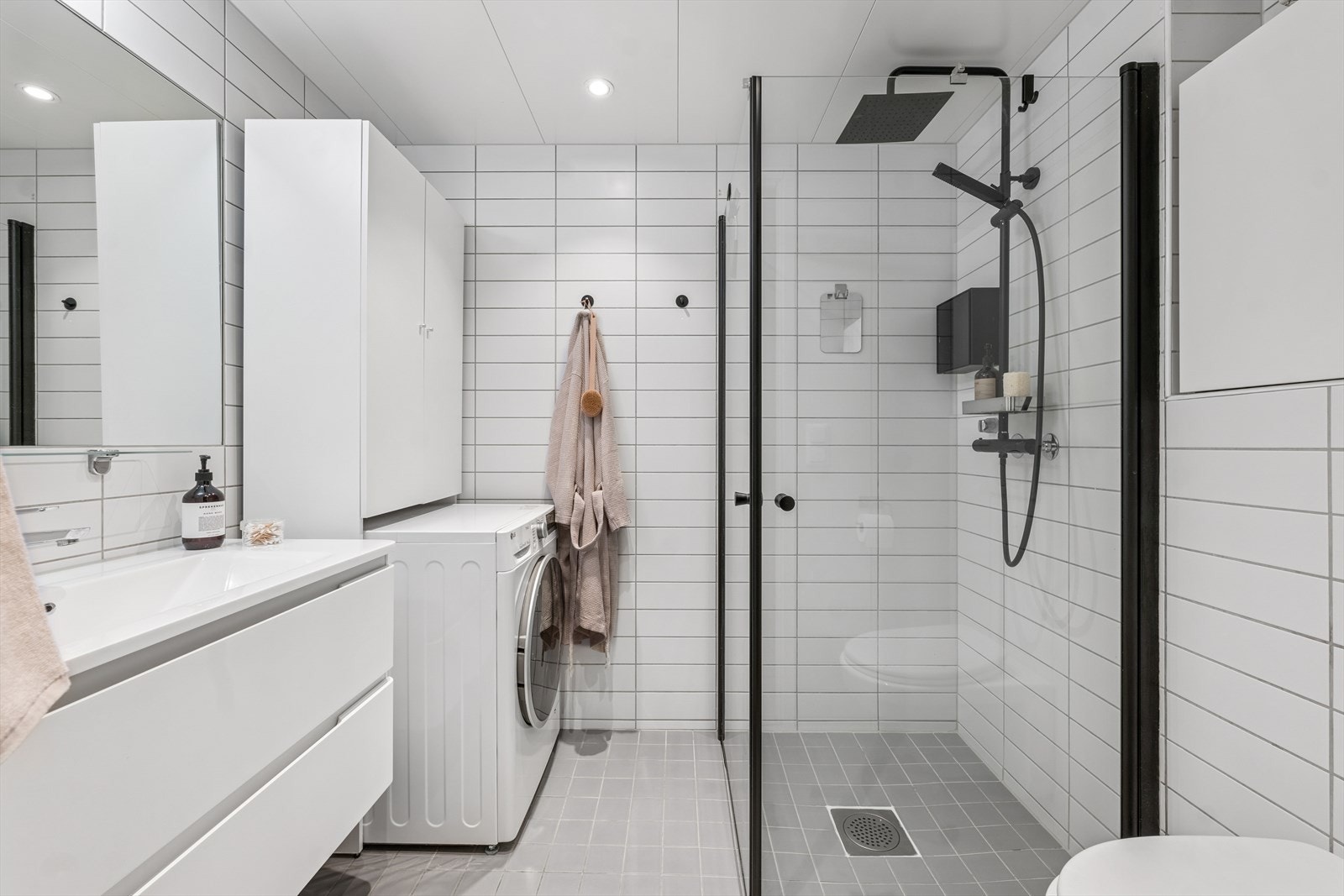 Stilrent flislagt baderom med lekre svarte detaljer og behagelige varmekabler i gulv. Galleribilde