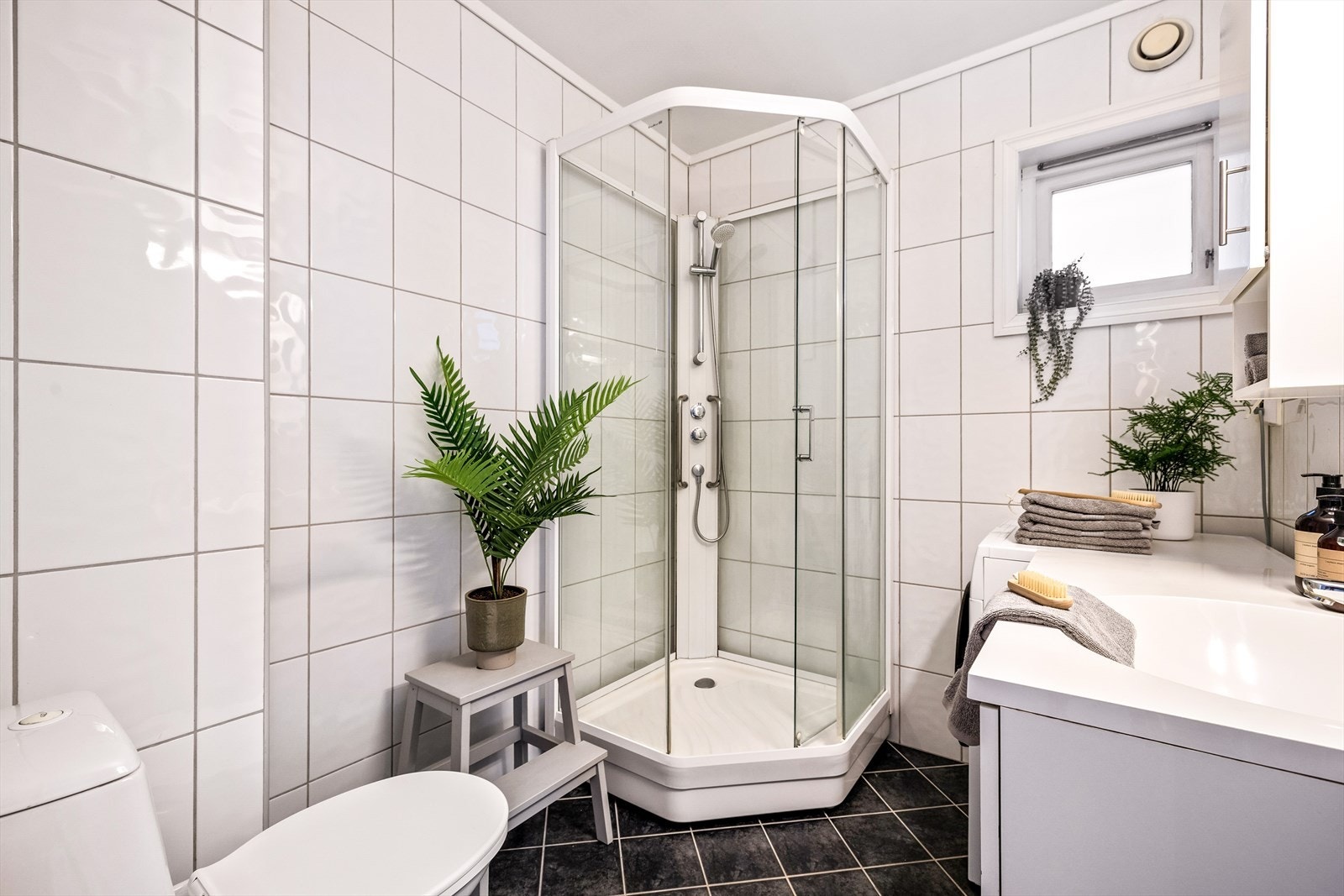 Pent helfliset bad innredet med wc, servant med møblement, speil, belysning og dusjkabinett. Galleribilde