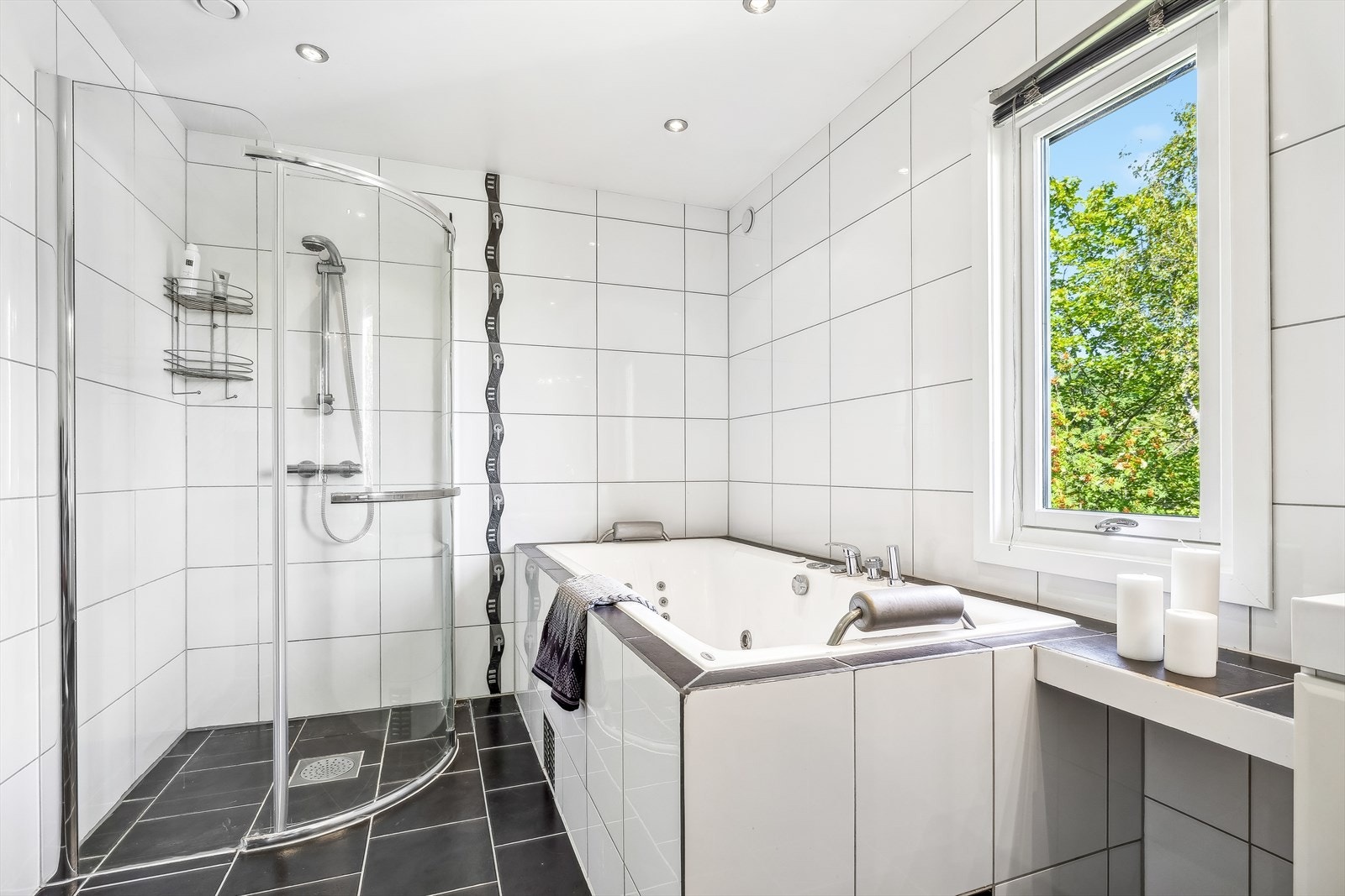 Badet er utstyrt med vegghengt toalett, innemurt boblebadekar, dusjhjørne med glassvegger, samt innredning med servant og speilskap. Galleribilde