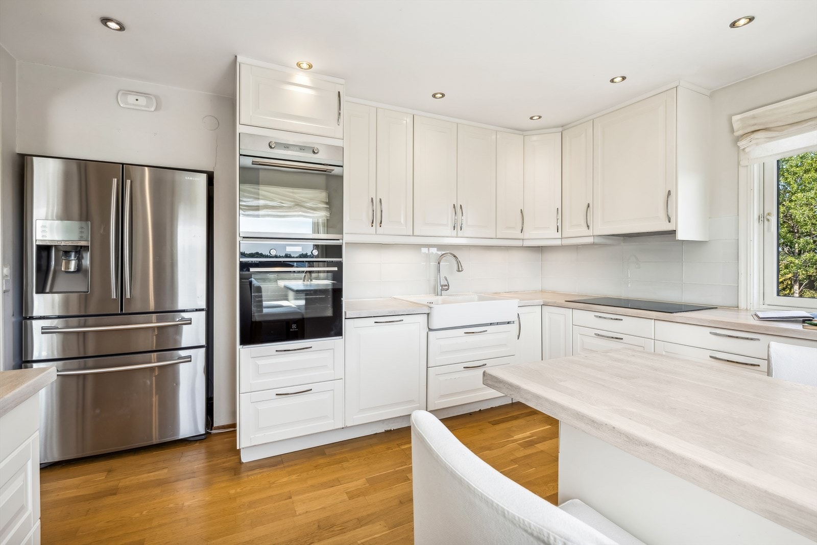 Kjøkkeninnredning med hvite profilerte fronter, heltre benkeplate og oppvaskkum. Galleribilde