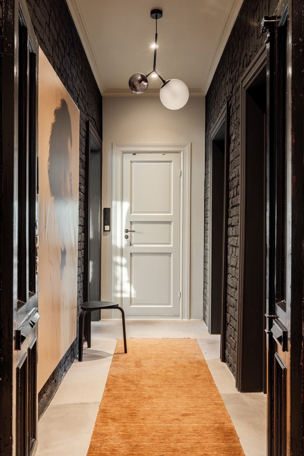 De fleste veggene, inkludert teglsteinen er malt svart og gir et røft uttrykk til rommet. Galleribilde