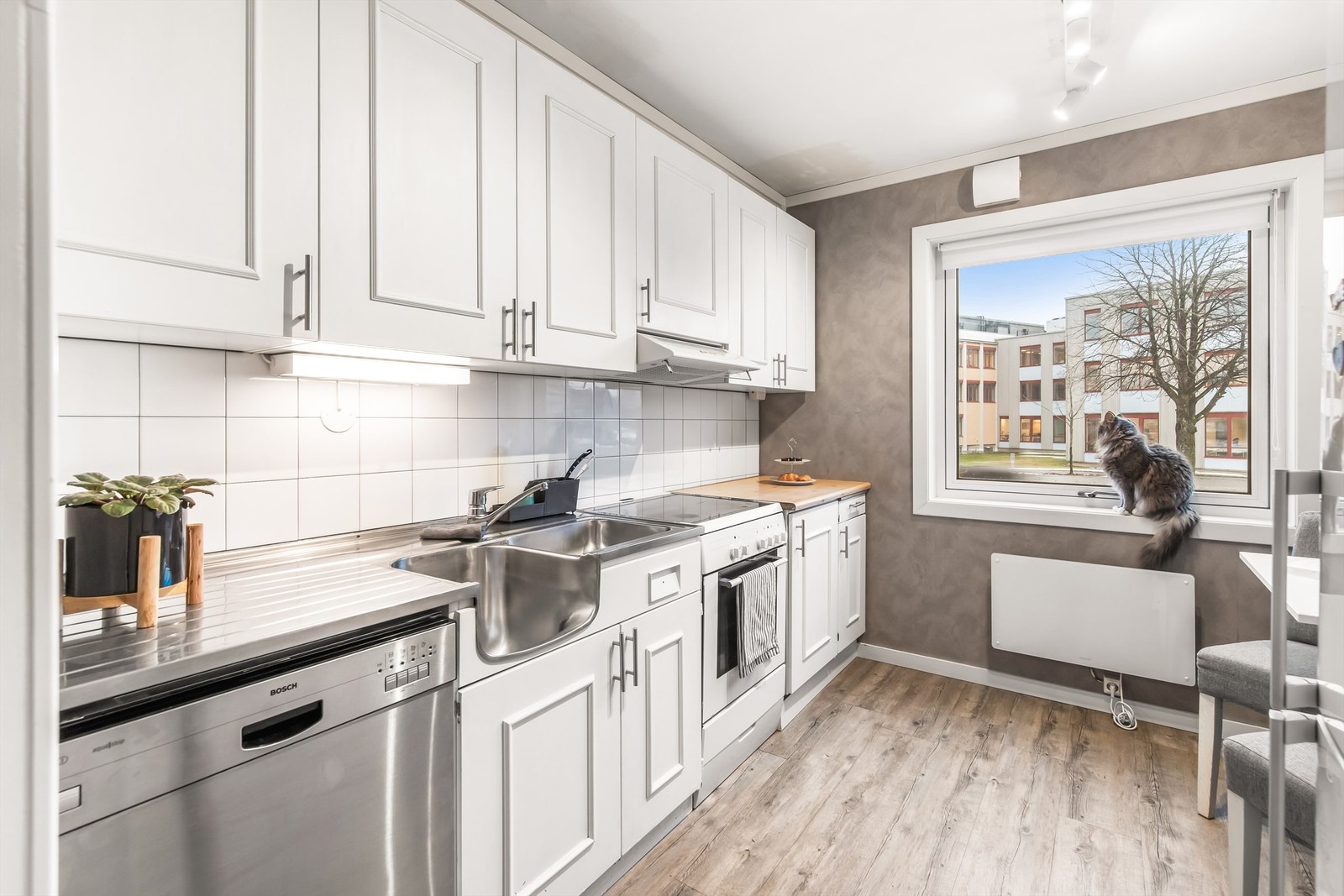 Kjøkkenet er pent og tidløst med hvitmalte profilerte fronter Galleribilde