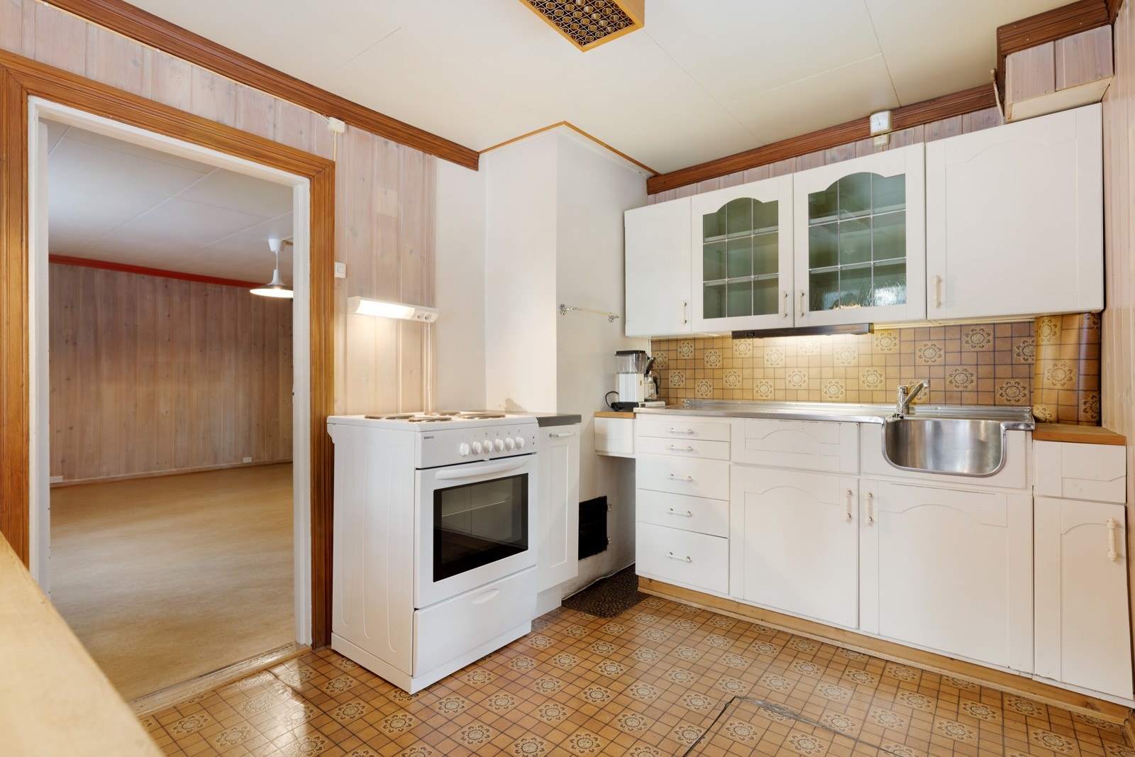 Lyst og koselig kjøkken. Innredning med glatte fronter og vitrineskap. Rustfritt benkebeslag med utslagsvask og oppvaskkum. Det plass til frittstående kjøleskap og komfyr. Galleribilde