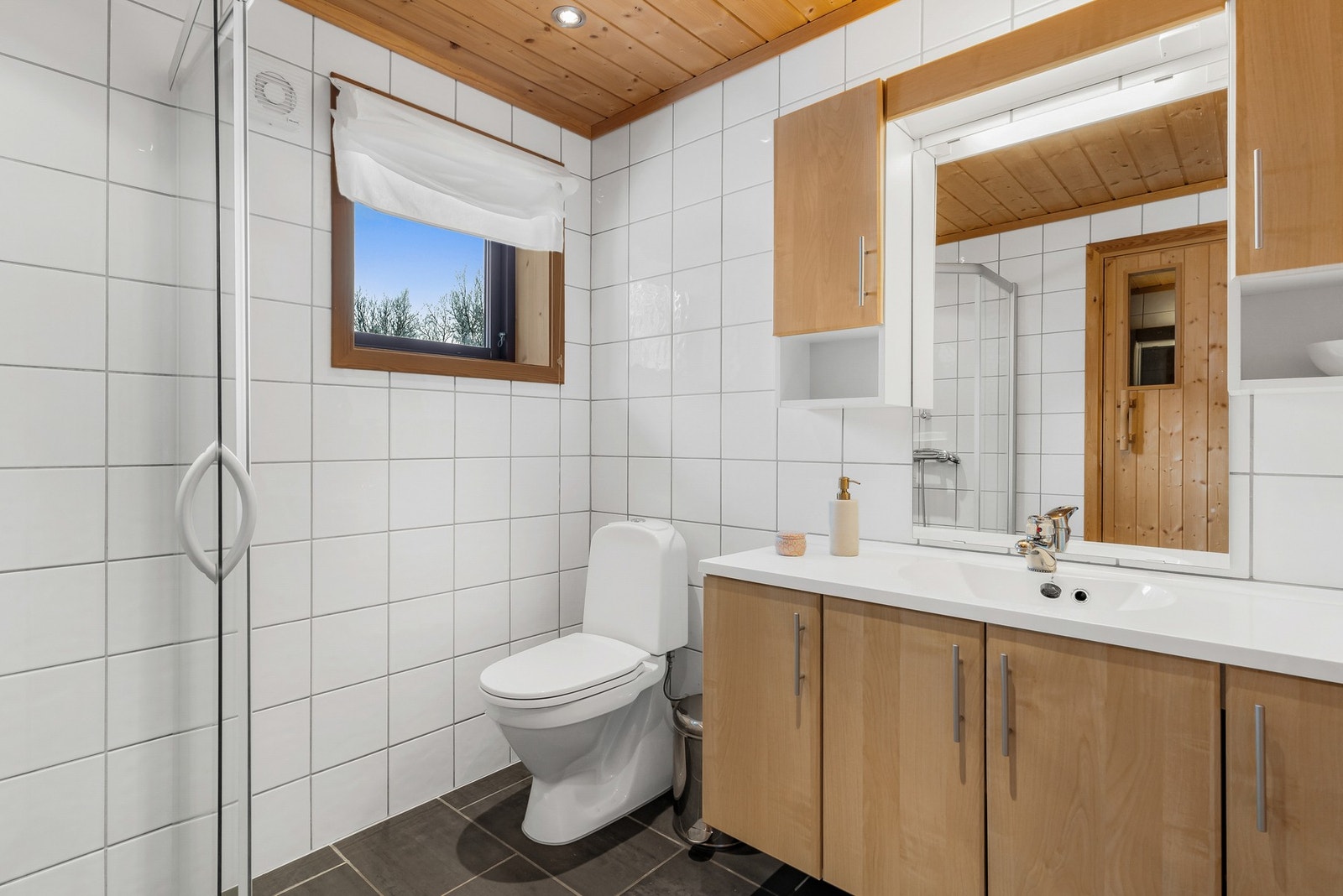 Badet er fra byggeår, og er utført av fagfolk. Her er det lagt fliser på gulv med varme, fliser på vegger og panel med downlights i himling. Galleribilde