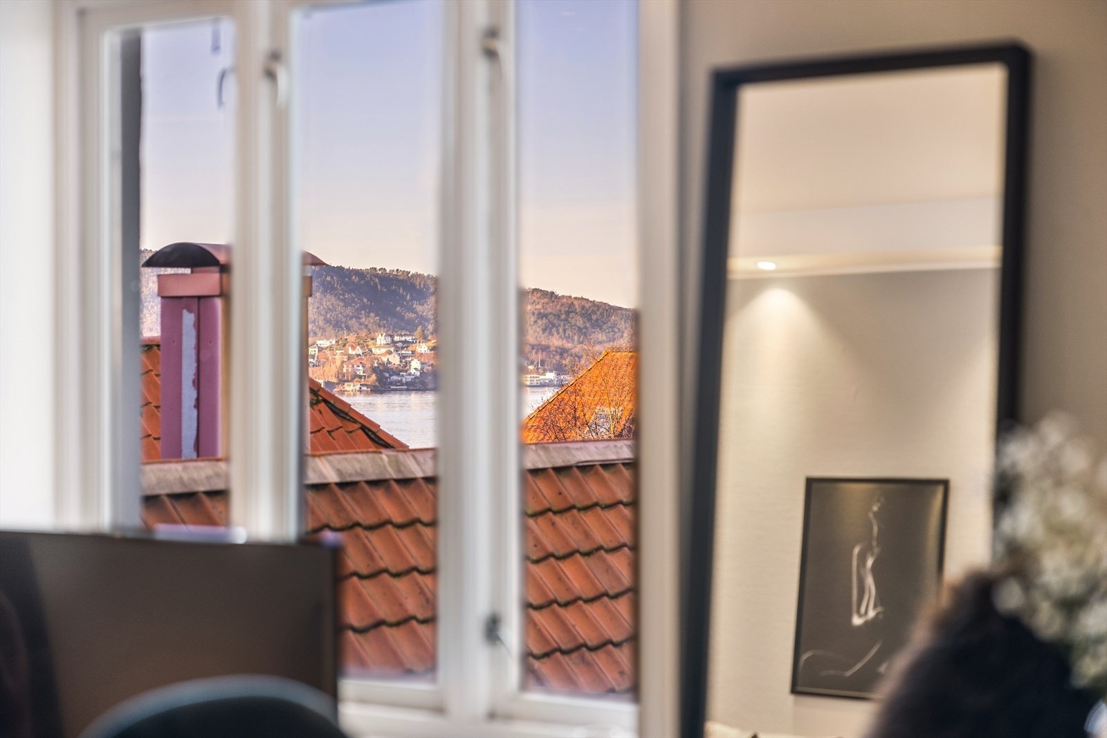 Fra stuen har du en koselig utsikt over hustak og sjøen. Galleribilde