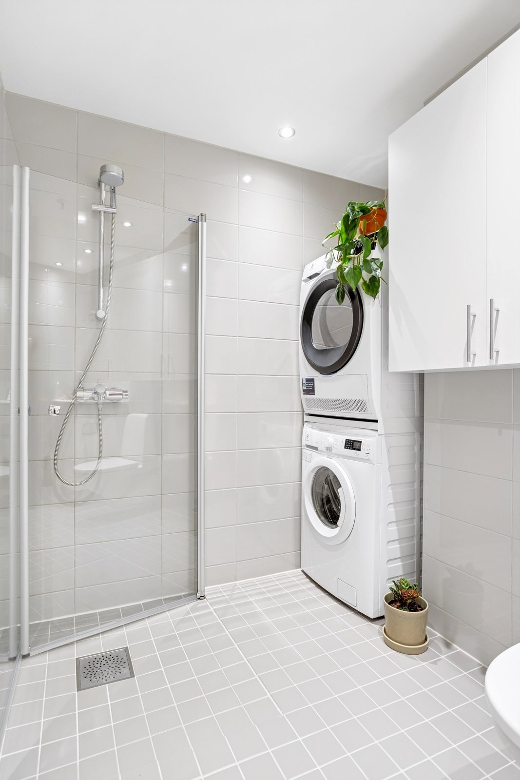 Innredning bestående av servantskap i hvit glatt utførelse med heldekkende servant, innfelt speil, overskap, vegghengt wc og dusjhjørne med svingdører. Det er opplegg for vaskemaskin/tørketrommel. Galleribilde