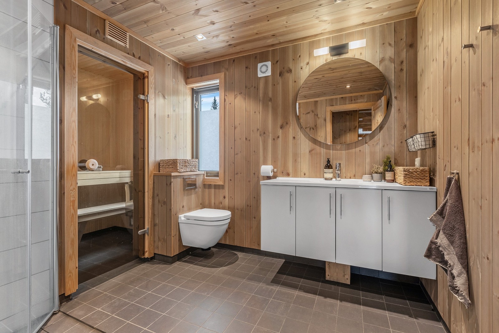 På badet er det lagt fliser med elektriske varmekabler på gulv, og en kombinasjon av fliser og panel/tømmer på veggene. Galleribilde