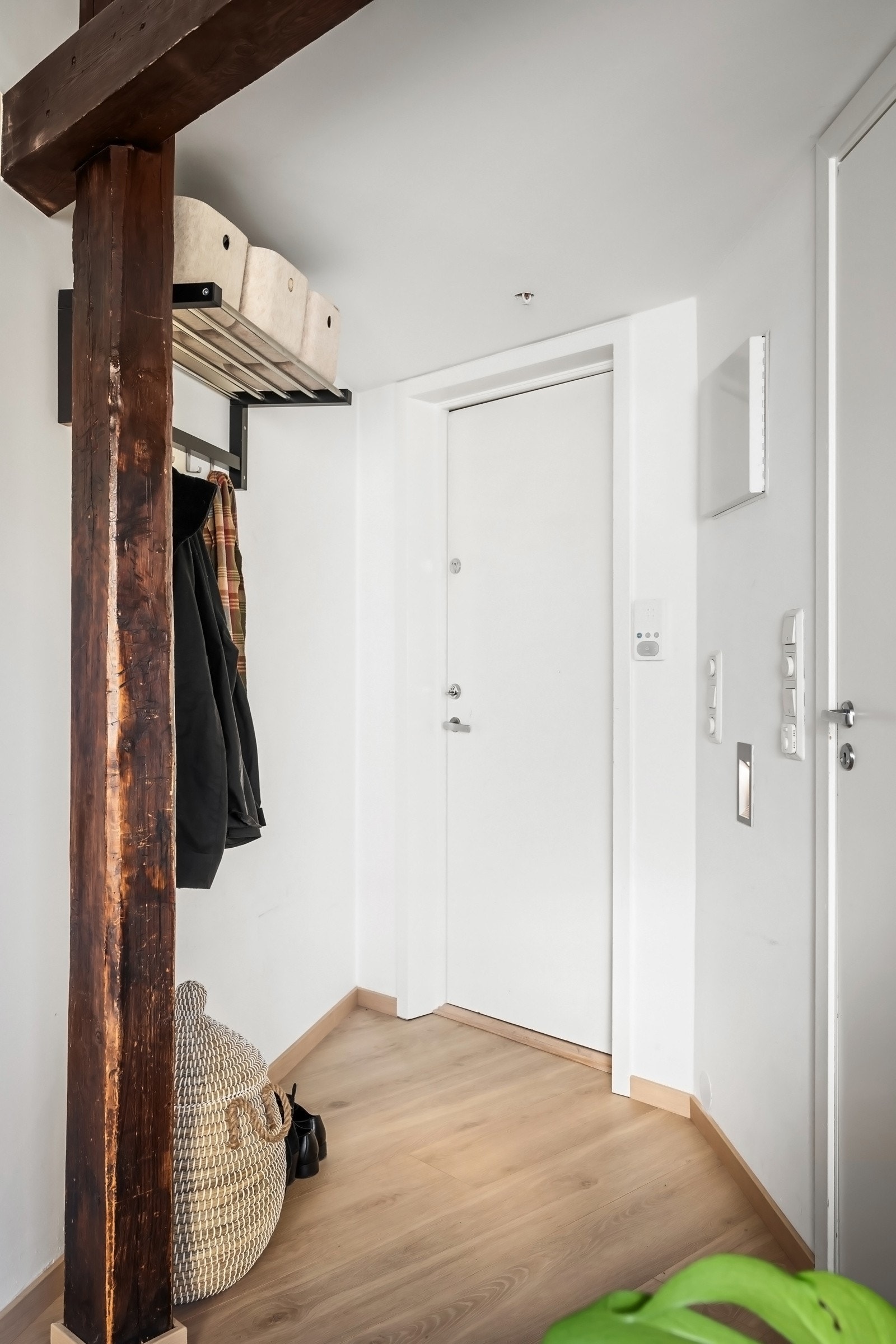 Entréen har lyse overflater og plass til oppheng av yttertøy samt skohylle. De gjennomgående trebjelkene gir leiligheten særpreg. Galleribilde