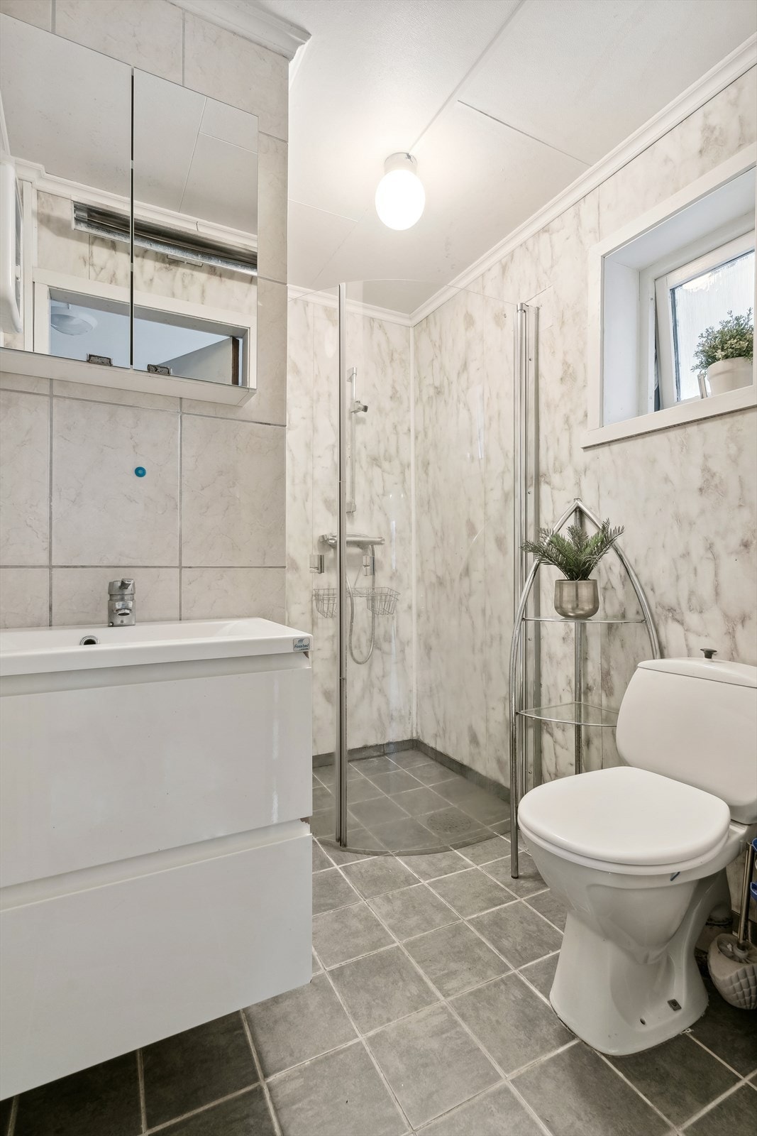 Baderom i 1.etasje. Av innreiing har du golvståande toalett, servantinnreiing, dusj på golv. Her har det oppstått vasslekkasje etter at bilete er tatt. Galleribilde