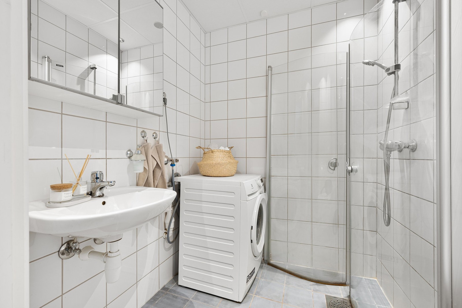 Lyst og flislagt baderom med opplegg til vaskemaskin. Galleribilde