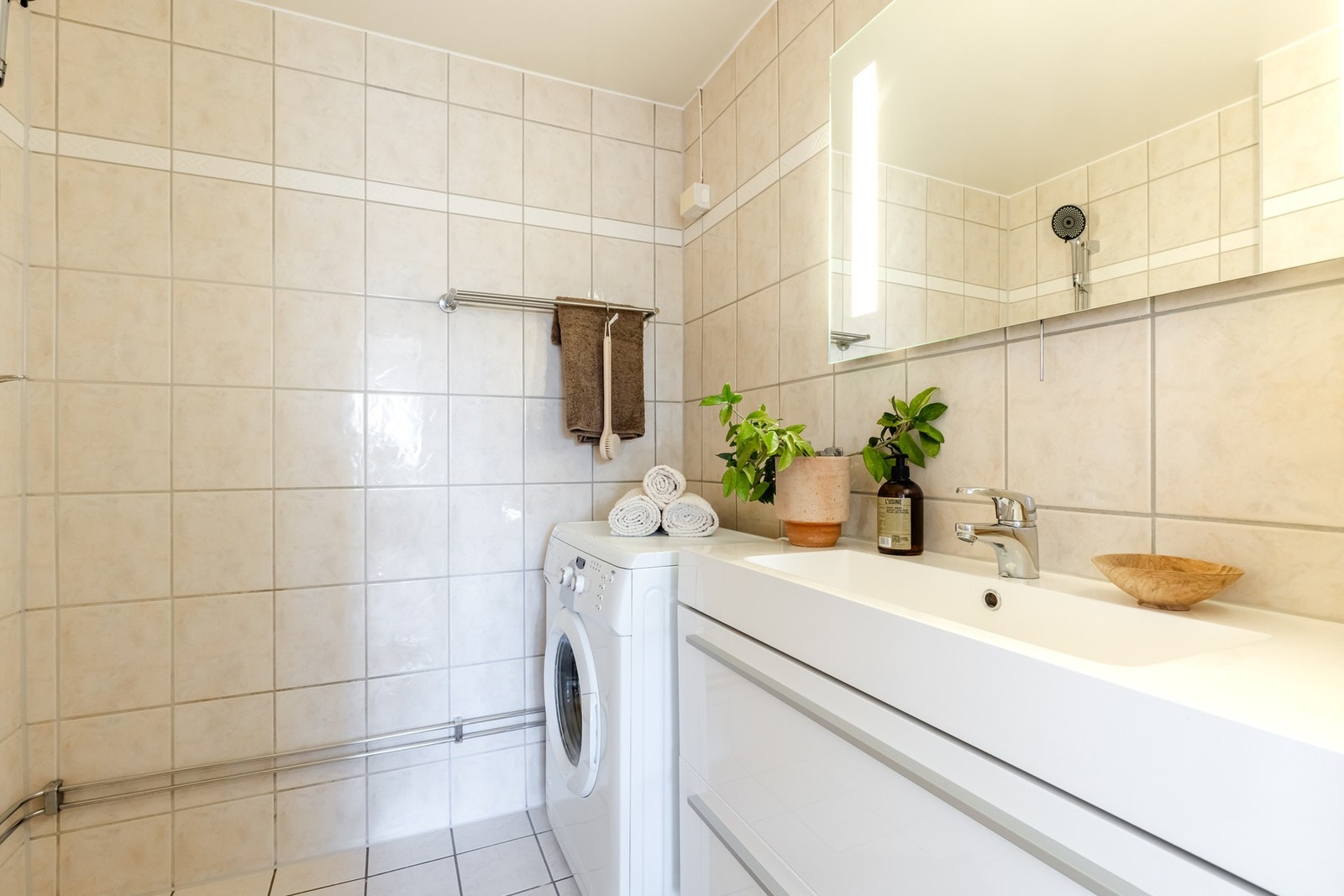 Praktisk og funksjonelt baderom med fliser på gulv og vegger, samt varme i gulv. Badet har opplegg/plass for vaskemaskin. Speil med innfelt lys ble montert i 2025. Galleribilde