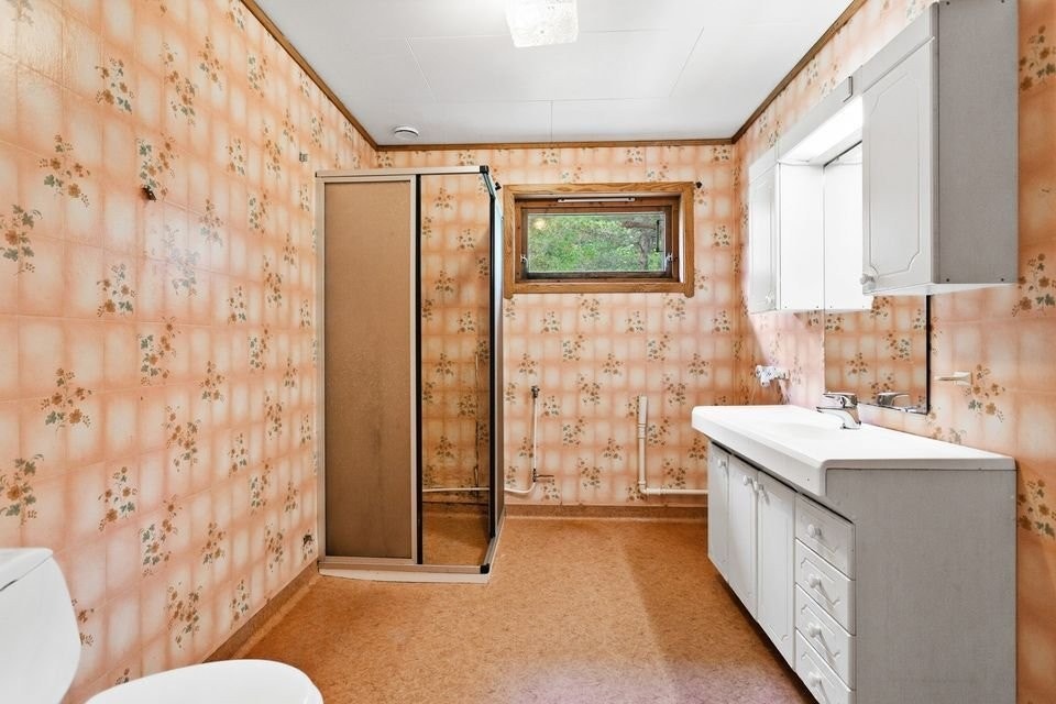 Bad med våtromstapet på veggene og himlingsplater i taket. Vinylbelegg på gulv. Innredning med nedfelt servant, toalett og dusjvegger/hjørne. Opplegg for vaskemaskin Galleribilde