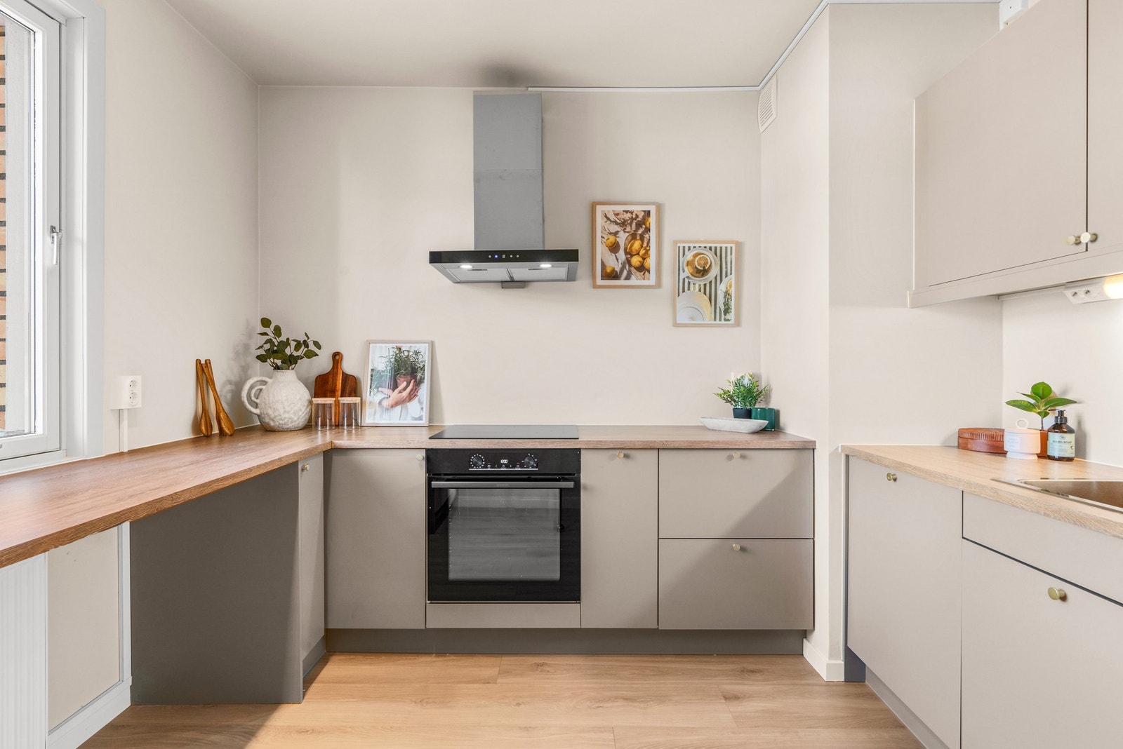 Innredningen fra Norema har glatte fronter i en dyp beigetone, kombinert med benkeplater i trehvit laminat og vaskekum i stål. Vinduet, spotbelysning i taket og god benkebelysning er med på å gi en ekstra lys og trivelig arbeidssone. Galleribilde