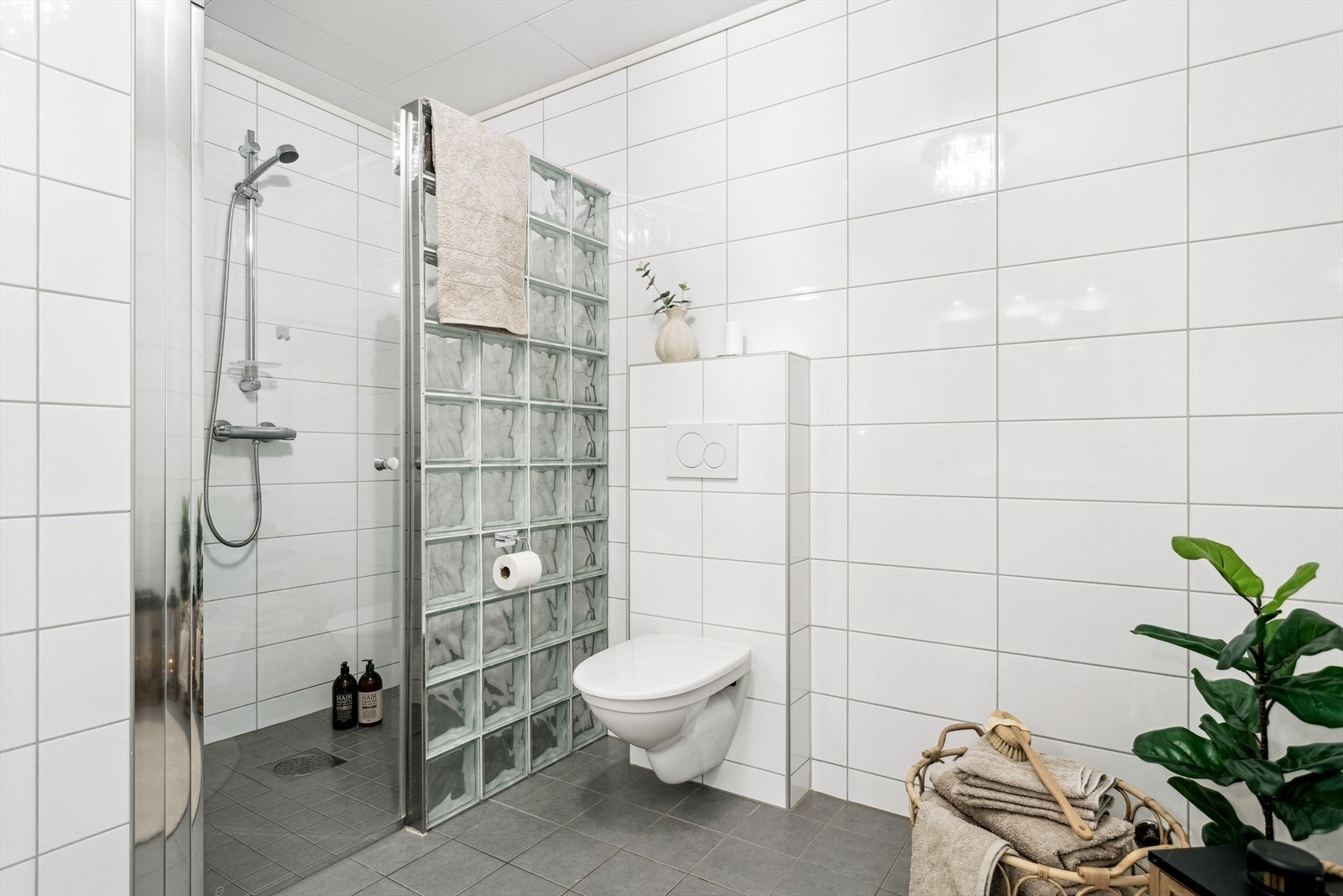 Badet er ca. 8 kvm og har en stor dusjnisje med vegg i glassbyggerstein. Det er opplegg for å ettermontere badekar. Galleribilde