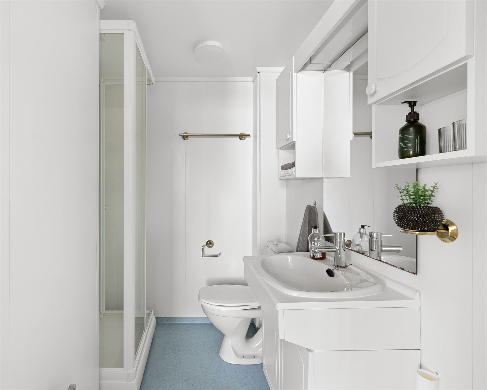 Bad med dusjkabinett, gulvstående WC og servant med underskap og speil med belysning Galleribilde