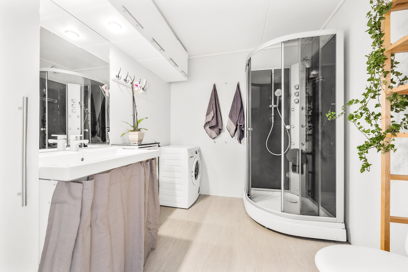 Innredet med moderne servantskap, speil med belysning, dusjkabinett med dusjarmatur og dyser, samt gulvmontert toalett. Opplegg til vaskemaskin Galleribilde
