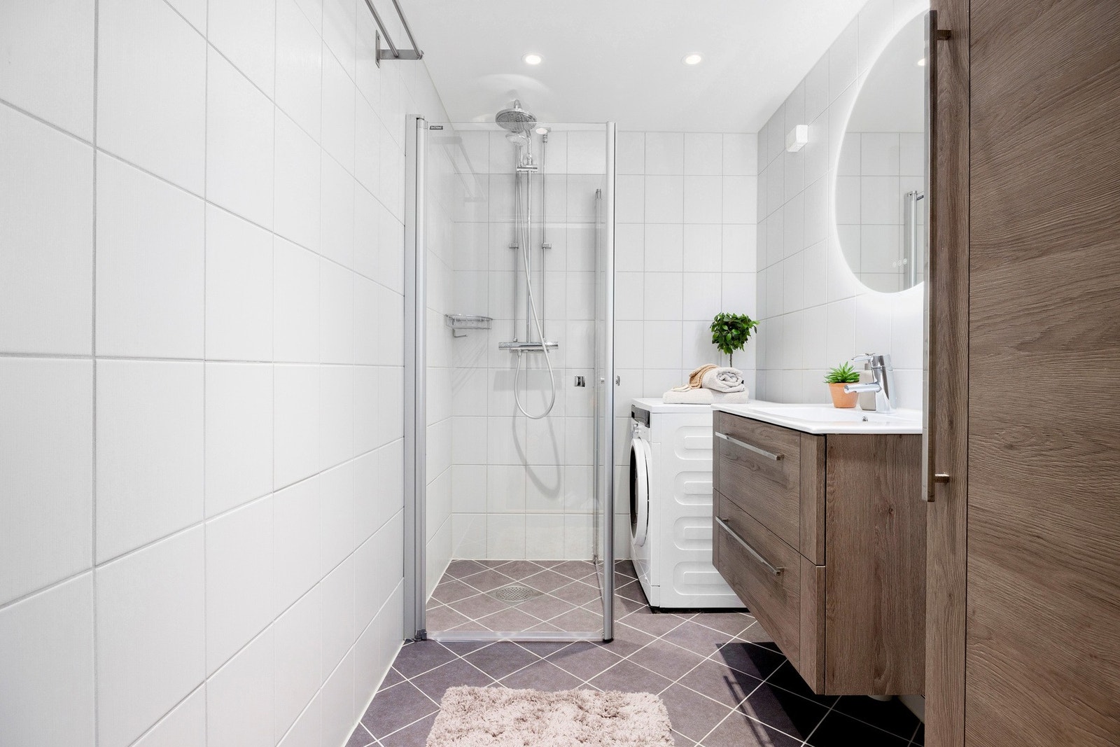 Pent, flislagt baderom med gulvvarme og downlightsbelysning i taket. Badet ble pusset opp i regi av borettslaget i 2018 og fremstår moderne. Her er det opplegg for vaskemaskin. Galleribilde