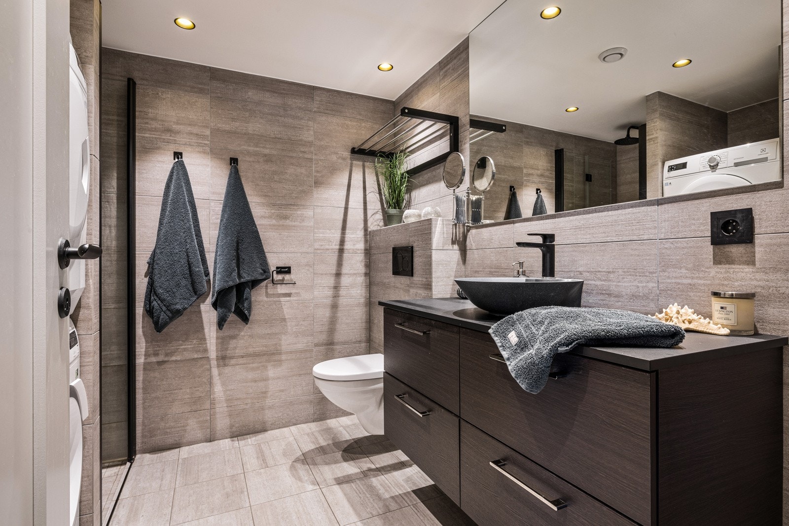 - Baderom nr. 1 er helfliset i delikate beige fliser og er innredet med vegghengt toalett, dusjnisje, stor baderomsinnredning med frittstående servant og speil - Galleribilde