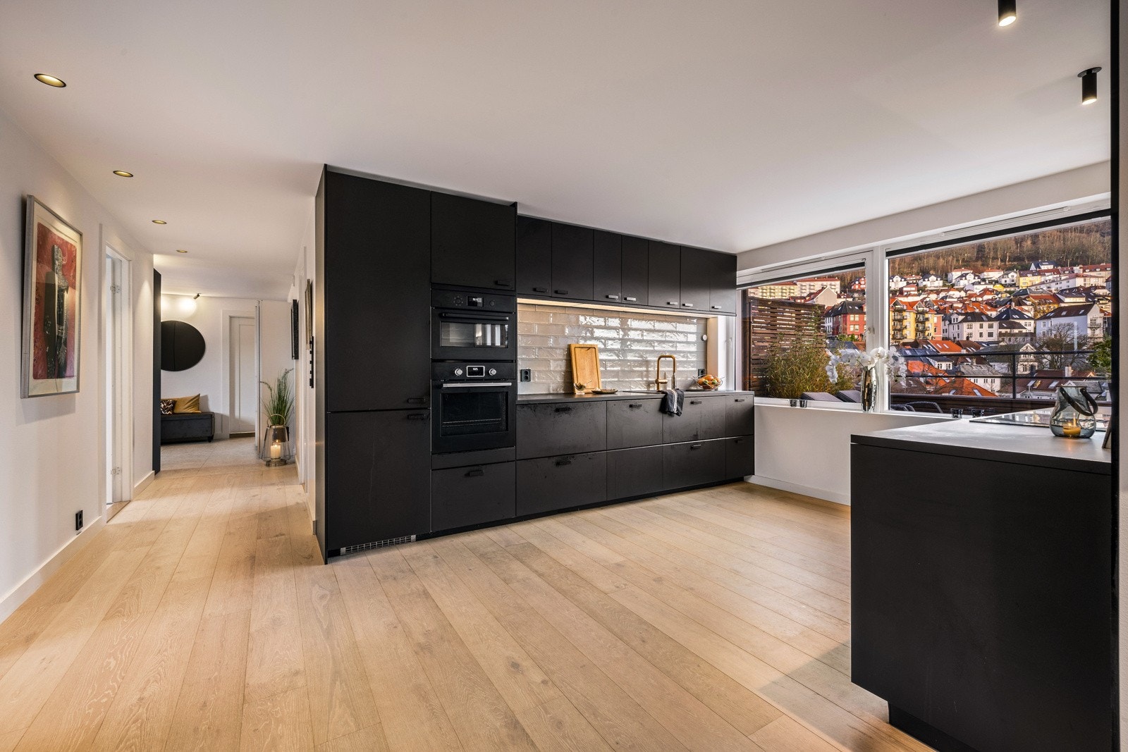 - Kjøkkenet ligger i dels åpen løsning og har en mørk, slett og takhøy innredning fra Ikea - Galleribilde