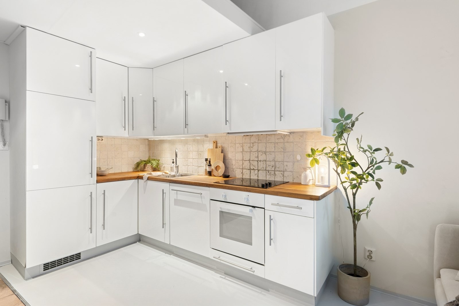 Kjøkkenet inneholder benkebelysning under overskap, integrert oppvaskmaskin, kjøle-/fryseskap, stekeovn og keramisk platetopp. Galleribilde