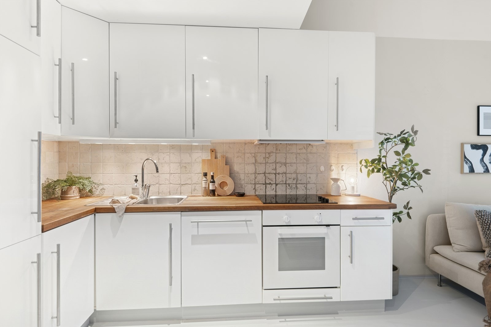 Ikea kjøkkeninnredning med glatte skapfronter i hvit høyglans. Unike fliser mellom benkeplate og overskap. Galleribilde