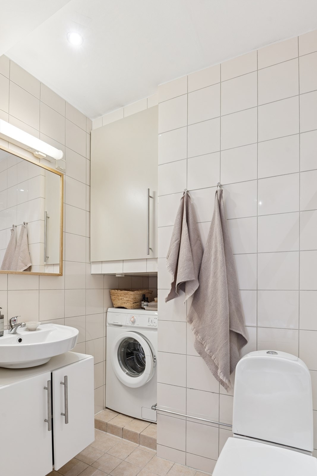 Videre inneholder badet gulvmontert toalett, servant med underskap, speil med belysning over servant, dusjhjørnet med hånddusj og regnfallsdusj. Galleribilde