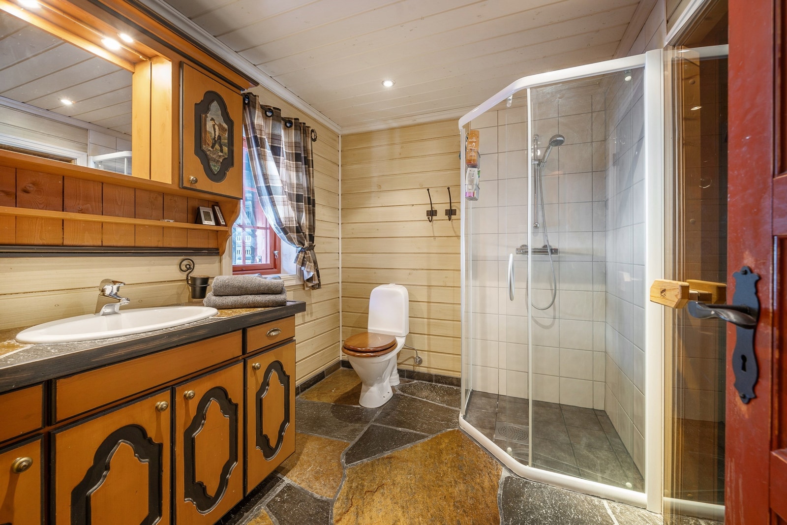 Bad med varmekabler i skifergulv, wc, dusjhjørne, servant med skap under. Inngang badstue. Galleribilde