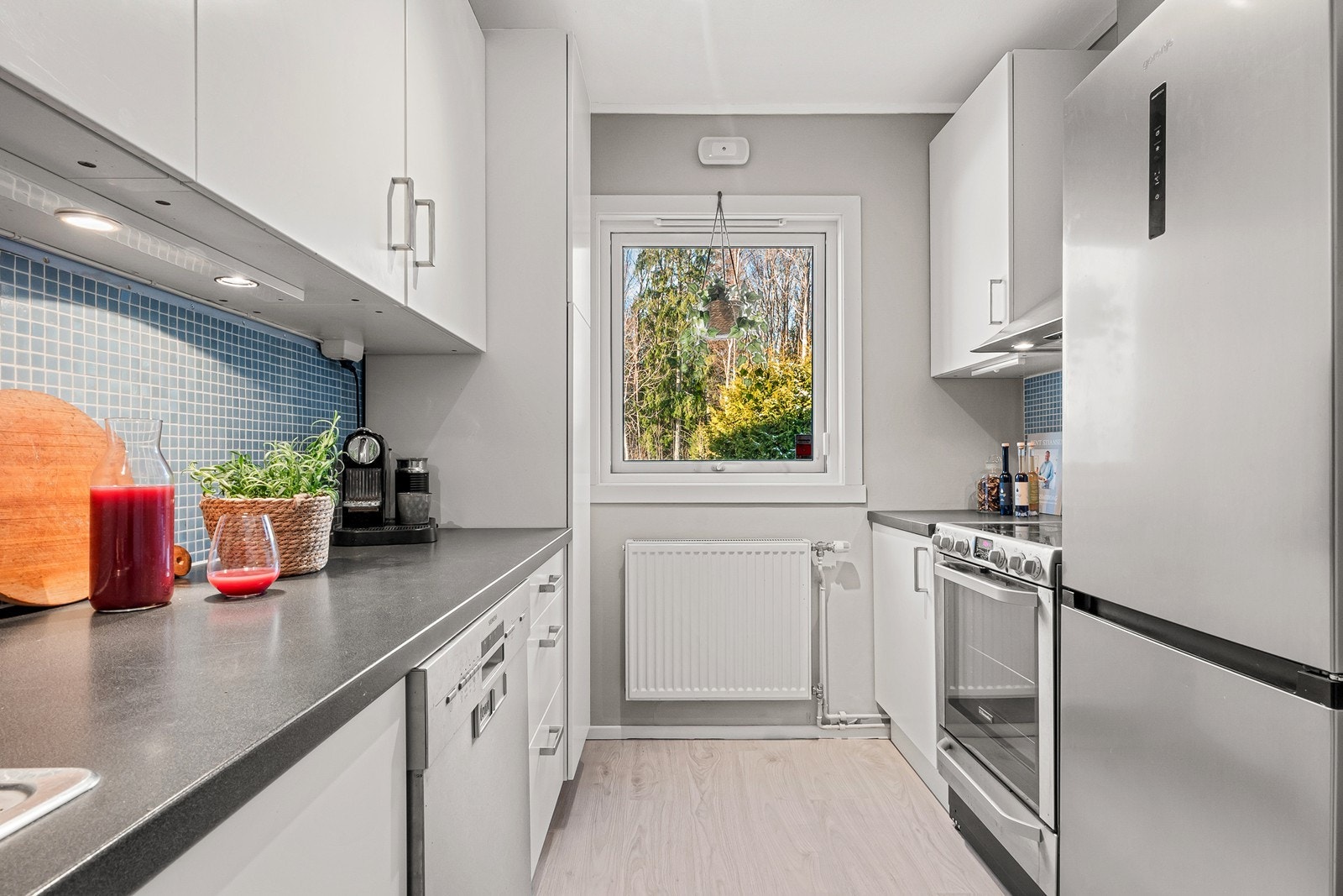 Kjøkkenet har innredning i over-, under- og høyskap med slette fronter plassert på to vegger parallelt i rommet. Galleribilde