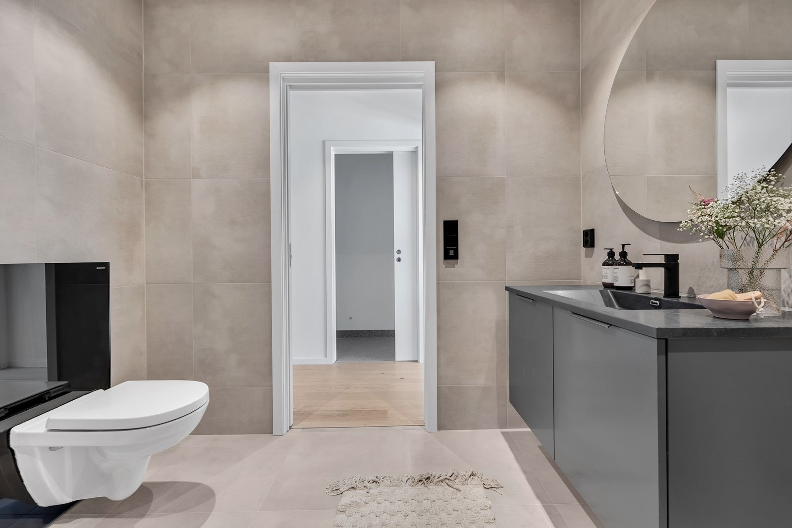 Badet er innredet med servant med skap, speil, vegghengt toalett og dusjhjørne. Galleribilde