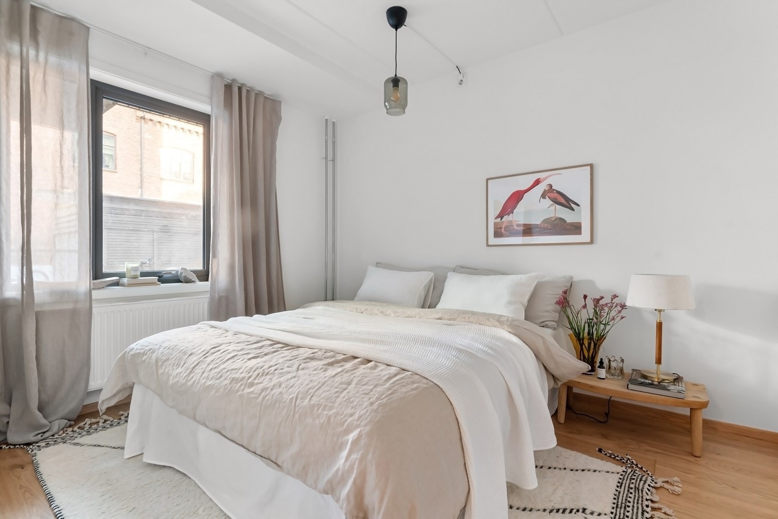 Lyst og tiltalende hovedsoverom med plass til dobbeltseng, nattbord og kommode Galleribilde