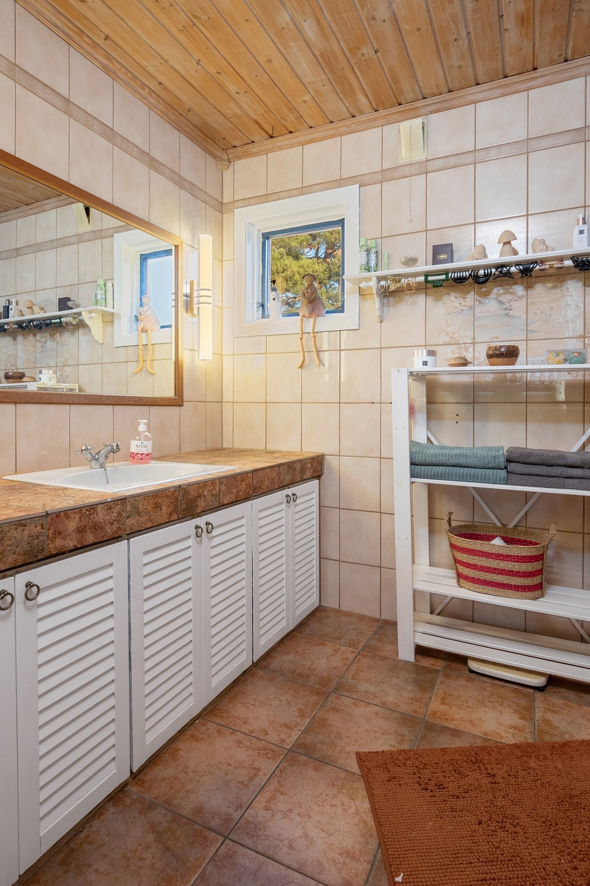 Innredningen består av en servant nedfelt i flislagt benk, hvite servantskap med sjalusiører, servantspeil med sidelys, et toalett og et dusjkabinett. Galleribilde