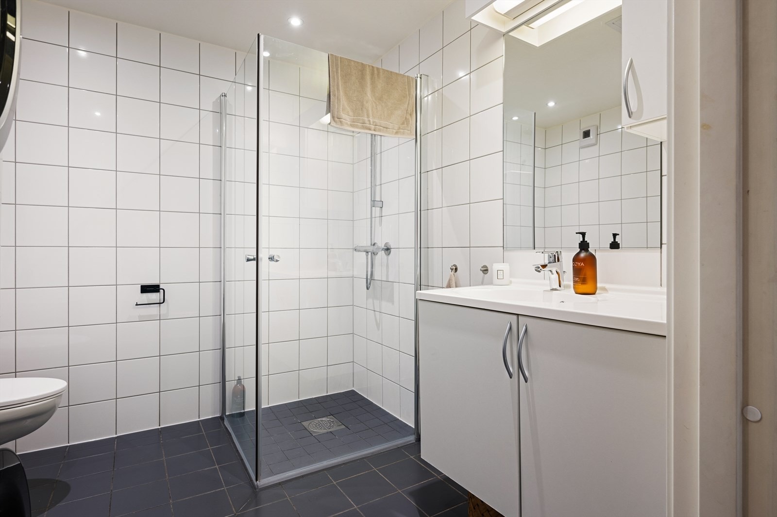 Tidløst bad med antrasittgrå gulvfliser, hvite veggfliser og vannbåren gulvvarme. Galleribilde