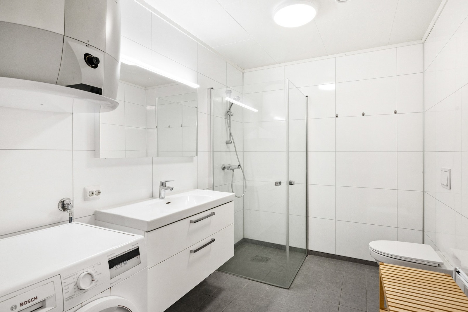 Bad/vaskerom med flislagt gulv og baderomsplater på vegger Galleribilde