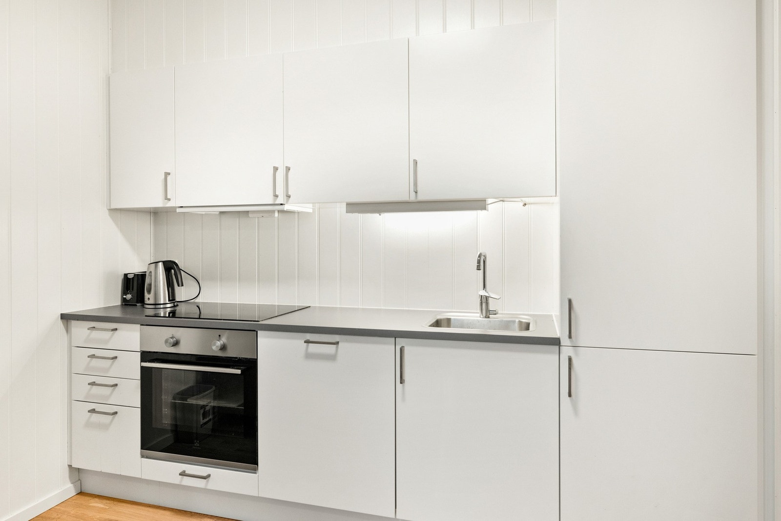 Kjøkkeninnredning med hvite slette fronter og mørk laminert benkeplate Galleribilde