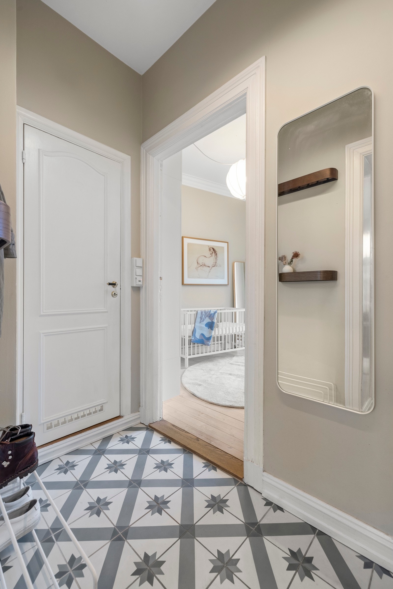 Gulvet i entrè har varmekabler og pene, historiske fliser. For øvrig har entreen slette, lysmalte vegger og ekstra god takhøyde, noe som er gjennomgående for leiligheten Galleribilde