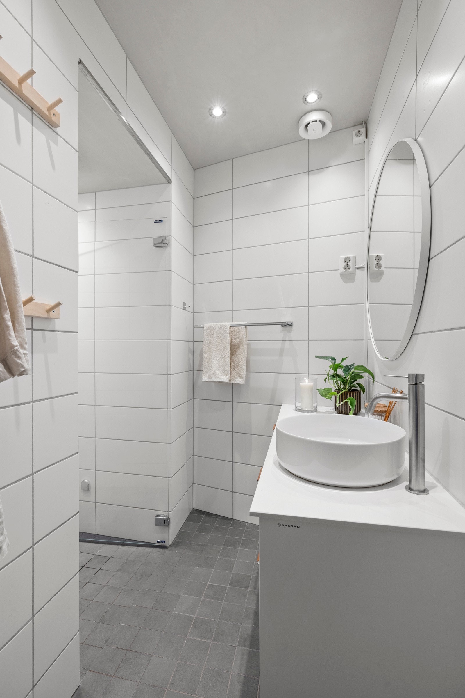 Badet er stilrent, med mørkegrå gulvfliser og hvite veggfliser. Det er utstyrt med gulvvarme, downlights Galleribilde