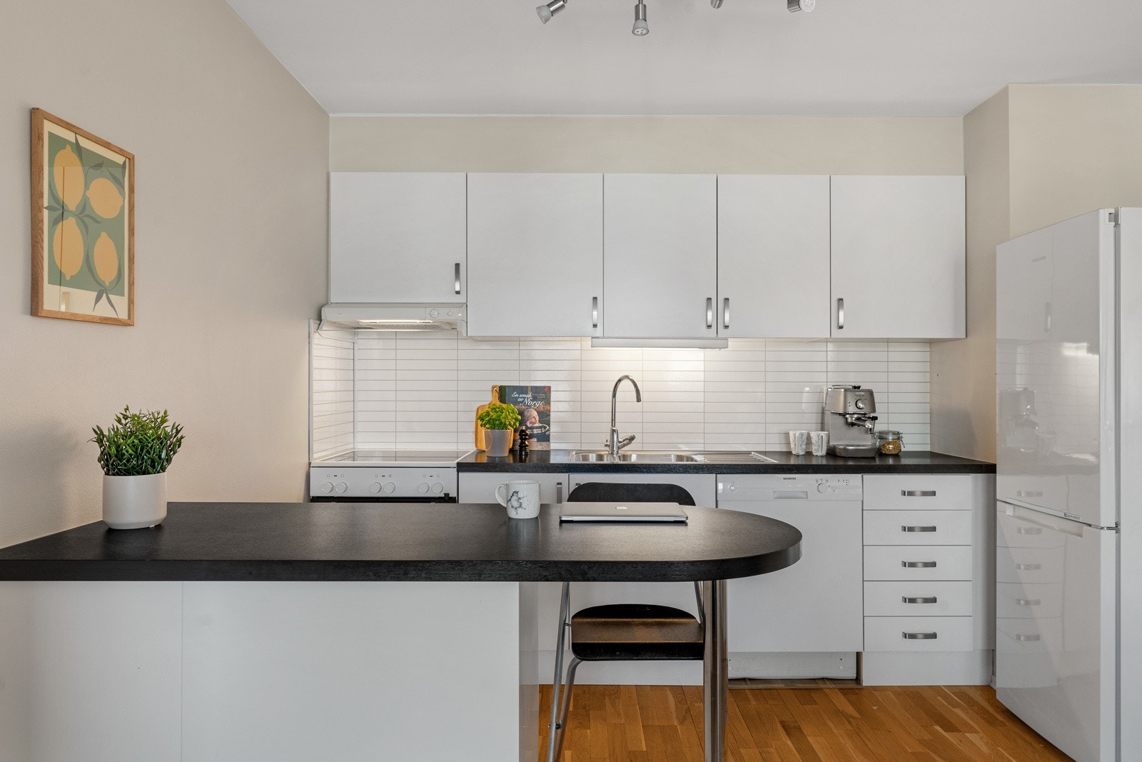 Kjøkkenet har en hvit innredning med godt med skap- og benkeplass. Galleribilde