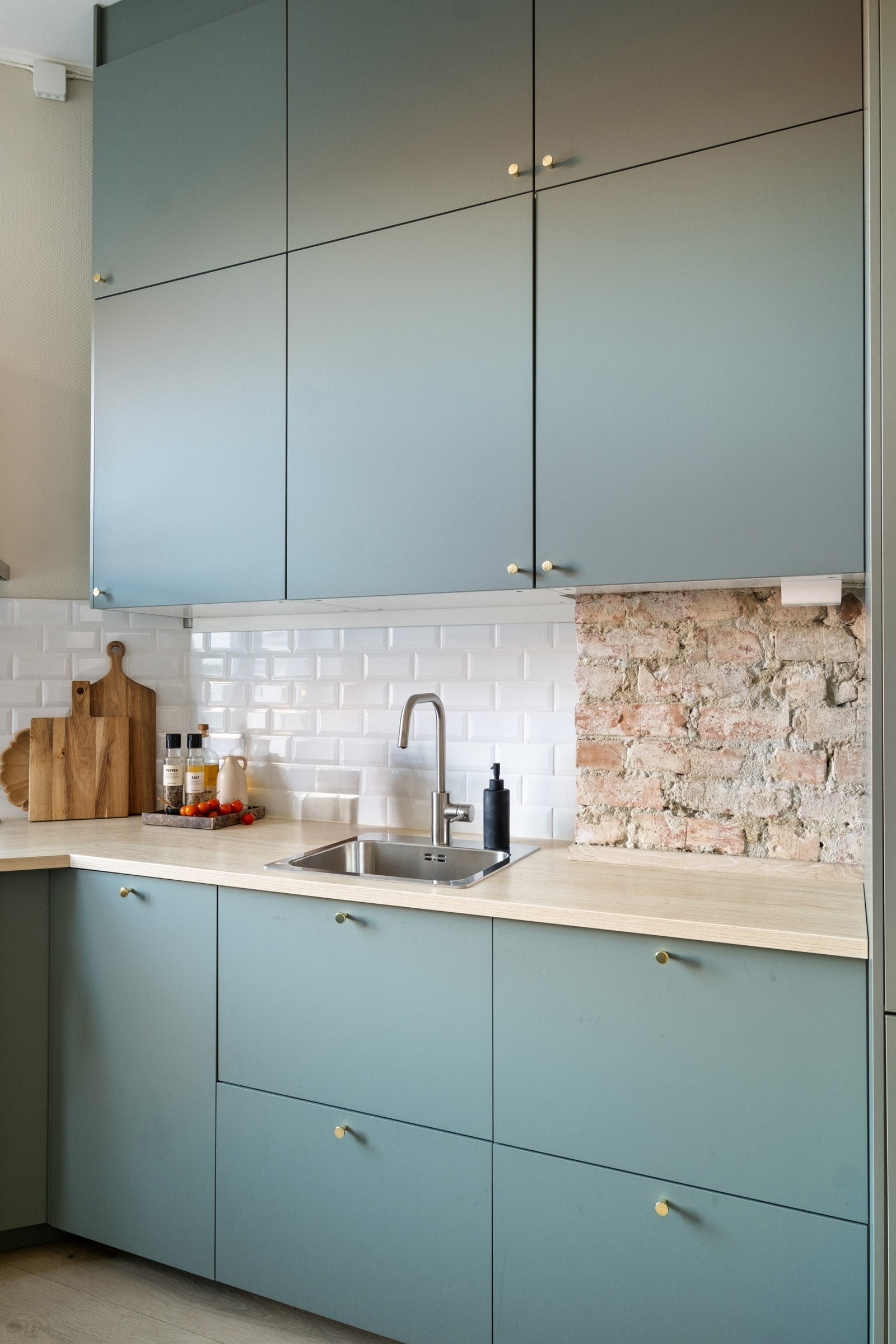 Over kjøkkenbenken er det synlig teglstein, som gir et klassisk element i det moderne kjøkkenet. Galleribilde